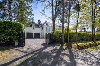 <section>
<div>
<div>
<div>
<div>
<div>
<div>
<p>In een prachtige residentiële wijk, met talrijke wandelpaden en natuur in de nabije omgeving, bevindt zich deze magnifieke villa op een royaal perceel van 2.415 m² met zuidgerichte tuin. De ligging biedt rust, privacy en wooncomfort, in een groene omgeving die uitnodigt tot wandelen en genieten.</p>
<p>Deze eigendom combineert uitzonderlijke volumes, hoogwaardige materialen en een bijzonder doordachte indeling. Al bij het betreden van de woning wordt u verwelkomd in een inkomhal met een hoogte van maar liefst 6,40 m. Het gevoel van licht, openheid en grandeur is hier meteen aanwezig. Het gelijkvloers heeft hoge plafonds van 3,20 m, massief eiken binnendeuren (2,50 m hoog) en een verfijnde afwerking met parketvloeren, gecombineerd met natuursteen.</p>
<p>De leefruimtes zijn royaal, lichtrijk en praktisch ingedeeld. Het gelijkvloers omvat een bureel, een tv-kamer, een woonkamer met open haard, een keukenruimte eveneens voorzien van open haard, een volledig ingerichte bijkeuken en een inpandige garage voor twee wagens. De verschillende ruimtes sluiten logisch op elkaar aan en creëren een aangename woonflow.</p>
<p>De woning is reeds afgewerkt met kwalitatieve materialen, met uitzondering van het keukeneiland en de badkamers. Deze kunnen door de koper nog volledig naar eigen smaak worden geïnstalleerd. Hierdoor vormt deze villa een blank canvas: een hoogwaardige en stijlvolle basis, met ruimte voor persoonlijke keuzes in de verdere afwerking.</p>
<p>Op de eerste verdieping bevinden zich meerdere slaapkamers, een royale mastersuite met dressing en badkamer, een wasplaats en een tweede badkamer. De zolderverdieping biedt bijkomende volwaardige kamers, een nachthal en technische ruimte.</p>
<p>Een uitzonderlijke villa met uitstraling, kwaliteit en toekomstwaarde.</p>
</div>
</div>
</div>
</div>
</div>
</div>
</section>
