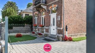 Deze statige, vrijstaande herenwoning ligt in de dorpskern van Eigenbilzen, vlak bij het Eigenbilzerplein en de Sint-Ursulakerk. De basisschool bevindt zich in het dorp. Ook winkels, het gezellige centrum en station van Bilzen en de verbindingswegen richting Maastricht, Genk en de E313 zijn vlot bereikbaar.<br /><br />De woning dateert van 1912 en staat op een zongericht perceel van 581 m². Ze omvat 208 m² bruikbare vloeroppervlakte en telt vier slaapkamers, aangevuld met verschillende praktische en multifunctionele ruimtes. Tussen 2019 en 2023 hebben de eigenaars de woning met veel liefde, kennis van haar geschiedenis en respect voor het oorspronkelijke karakter grondig gerenoveerd. Authentieke elementen werden daarbij zorgvuldig bewaard en gecombineerd met hedendaags wooncomfort en energiezuinige ingrepen.<br /><br />De markante bakstenen gevel met rondboogvensters, hardstenen accenten en sierbalkon geeft meteen aan dat dit geen alledaagse woning is. Ook het fraaie smeedijzeren voortuinhek draagt bij aan de uitstraling. Het zwart-wit geschilderde hekwerk dateert uit de eerste helft van de twintigste eeuw en is vanwege zijn erfgoedwaarde opgenomen in de Inventaris Onroerend Erfgoed. Verder is de woning vrijgesteld van deze inventaris. <br /><br />Binnen bleven eveneens verschillende kenmerkende elementen zichtbaar. Hoge plafonds, de originele parketvloeren, gerestaureerde binnendeuren en rijk uitgewerkte schouwmantels zorgen voor een warme, doorleefde uitstraling.<br /><br />Indeling<br /><br />Via de inkomhal met afzonderlijk gastentoilet bereik je de woonvertrekken. Aan de voorzijde ligt de woonkamer, waar de hoge plafonds van ca. 3,5 meter en de grote ramen voor een aangenaam ruimtegevoel en veel natuurlijke lichtinval zorgen. De sierlijke schouwmantel vormt hier een opvallend onderdeel van het interieur.<br /><br />Aansluitend bevindt zich de eetkamer met opnieuw een hoge plafondhoogte en een brede raampartij. De opeenvolging van woonkamer en eetkamer sluit aan bij de klassieke indeling van het pand en biedt tegelijk voldoende ruimte voor het dagelijkse gezinsleven.<br /><br />De keuken werd in 2023 volledig vernieuwd en sluit qua vormgeving mooi aan bij de stijl van de woning. Donkere kastfronten, een houten werkblad, messingkleurig beslag en een opvallende fornuisombouw met decoratieve reliëftegels vormen samen een bijzonder geheel. De keuken is uitgerust met een keramische kookplaat, een koelkast met diepvriesgedeelte, een vaatwasser en een afzonderlijke oven en microgolfoven.<br /><br />Achteraan bevindt zich de royale glazen tuinkamer. Het glazen dak en de brede schuifpartijen laten veel daglicht binnen en zorgen voor een rechtstreekse verbinding met de tuin. De oorspronkelijke bakstenen achtergevel bleef hier zichtbaar en vormt een karaktervolle achtergrond. Deze ruimte is voorzien van verwarming en kan het hele jaar door gebruikt worden als eetplaats, tweede zithoek of plek om rustig van de tuin te genieten.<br /><br />Verder beschikt het gelijkvloers over een praktische berging en een afzonderlijk ingerichte wasruimte met plaats voor huishoudtoestellen en voorraad.<br /><br />Op de eerste verdieping leidt de overloop naar twee slaapkamers. Ook hier zorgen de hoge ramen, houten vloeren en aanwezige schouwmantels voor een sfeer die veel weg heeft van een boutique-hotel. De badkamer werd in 2022 volledig vernieuwd en is ingericht met een ruime inloopdouche, een badkamermeubel met lavabo en een toilet. De witte afwerking, glazen kroonluchter en blauw getinte decoratieve tegels geven de ruimte een frisse, verzorgde uitstraling.<br /><br />Een vaste trap brengt je naar de ingerichte bovenverdieping. Hier bevinden zich twee bijkomende kamers, waardoor de woning in totaal vier slaapkamers telt. Afhankelijk van de behoefte kunnen deze ruimtes ook worden ingericht als bureau, hobbykamer, logeerkamer of extra leefruimte.<br /><br />Vooral de open ruimte onder het dak is bijzonder. Het hoge plafond, het vrijgelegde houten gebinte en de zichtbaar gehouden delen van de baksteenstructuur geven deze verdieping een uitgesproken karakter. De authentieke materialen maken de geschiedenis van het pand tastbaar, terwijl de eigentijdse afwerking voor een persoonlijke en comfortabele woonomgeving zorgt. <br /><br />De kelder van circa 25 m² biedt bijkomende plaats voor voorraad en de technische installatie.<br /><br />Ook buiten werd de woning verzorgd aangepakt. De glazen tuinkamer opent volledig naar het terras en de tuin. De bestrating en volwassen groene omkadering zorgen voor een aangename buitenruimte met de nodige privacy. Aan de zijkant bevindt zich een brede oprit en voor de woning zijn twee parkeerplaatsen beschikbaar. Als kers op de taart wordt de oprit nog afgewerkt met een toegangspoort. <br /><br />Ook technisch werden belangrijke investeringen uitgevoerd. De elektrische installatie, riolering, waterleidingen, verwarmingsleidingen en radiatoren werden vernieuwd. De woning beschikt over een condenserende gasketel van ATAG, een waterontharder en pvc- en aluminium buitenschrijnwerk met hoogrendementsbeglazing. Daarnaast werden het dak, de muren en een groot deel van de vloeren geïsoleerd. Deze ingrepen resulteren in een EPC-label C met een energiescore van 278 kWh/(m² jaar).<br /><br />Belangrijkste troeven:<br /><br />- Statige, vrijstaande herenwoning uit 1912<br />- Gelegen in de dorpskern, vlak bij het Eigenbilzerplein<br />- 208 m² bruikbare vloeroppervlakte volgens het EPC<br />- Vier slaapkamers en verschillende multifunctionele ruimtes<br />- Grondige totaalrenovatie uitgevoerd tussen 2019 en 2023<br />- Met liefde en respect voor het oorspronkelijke karakter gerenoveerd<br />- Hoge plafonds, houten vloeren en rijk uitgewerkte schouwmantels<br />- Vrijgelegd houten gebinte en zichtbaar baksteenwerk<br />- Historisch smeedijzeren voortuinhek met erfgoedwaarde<br />- Vernieuwde keuken met een uitgesproken, karaktervolle afwerking<br />- Royale glazen tuinkamer met brede schuifpartijen<br />- Vernieuwde badkamer en praktische wasruimte<br />- Vernieuwde technieken en doorgedreven isolatiewerken<br />- EPC-label C<br />- Zongericht perceel van 581 m²<br /><br />Deze woning richt zich tot wie houdt van een pand met geschiedenis, ruimte en een uitgesproken eigen karakter, zonder afstand te willen doen van hedendaags wooncomfort.<br /><br />Wil je deze bijzondere herenwoning zelf ontdekken? Neem contact op met Immofair via 089 390 990 of info@immofair.be voor meer informatie of een persoonlijke bezichtiging.