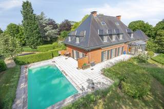 <p><strong><em>Villa élégante (584 m²) avec 7 chambres, 2 dressings, salle de bain et salle de douche, bureau + espace de travail, double garage, grenier, cave, grande terrasse avec piscine et magnifique jardin de parc avec court de tennis sur une parcelle de 51a 14ca offrant une grande intimité à Herent.</em></strong><br /><strong><em>Possibilités certaines pour une maison kangourou, bureau, cabinet ou profession libérale.</em></strong></p><p>Située dans un endroit calme et très privé, cette villa raffinée dévoile une habitation spacieuse où chaleur et générosité se mêlent naturellement. Avec ses vastes espaces de vie, ses sept chambres, ses deux dressings, ses espaces de travail et son jardin de parc étendu, cette maison constitue un lieu de vie particulièrement accueillant pour ceux qui recherchent confort, élégance et polyvalence.</p><p>Le large hall d’entrée avec vestiaire et toilette invités mène à un séjour lumineux en forme de L, agrémenté de pierre naturelle, d’un foyer au gaz intégré et de mobilier sur mesure apportant calme et raffinement. Les grandes baies vitrées offrent une vue superbe sur le jardin et un accès direct à la vaste terrasse.<br />La cuisine attenante, aménagée avec goût, présente des plans de travail en pierre naturelle, un parquet massif et une charmante baie vitrée avec coin repas donnant sur la verdure.</p><p>Au rez-de-chaussée se trouve également un bureau spacieux de 31 m², complété par un espace de travail de 41 m² équipé de l’air conditionné. Cette aile est idéale pour une pratique, une profession libérale ou un bureau à domicile.<br />Le double garage et l’allée permettent un stationnement confortable.</p><p>Le premier étage dévoile un hall de nuit central avec toilette séparée, une salle de bain rénovée en pierre naturelle avec baignoire et douche, une salle de douche distincte et pas moins de sept chambres, dont certaines avec placards intégrés et lavabo. La chambre principale dispose de deux dressings séparés, renforçant la sensation d’espace et de luxe.</p><p>Au-dessus, un grand grenier de 88 m² offre des possibilités d’extension pour ceux qui souhaitent encore davantage d’espace.<br />La cave (30 m²) comprend notamment une installation de chauffage récemment remplacée, un adoucisseur d’eau et une cave à vin réfrigérée. Un vide sanitaire est également présent.</p><p>À l’extérieur, la terrasse de 82 m² constitue un lieu de détente privilégié, directement relié à la piscine chauffée orientée plein sud.<br />Le jardin de parc paysager respire la tranquillité et l’intimité, et comprend un court de tennis entièrement aménagé, un atout supplémentaire rare sur un domaine de cette qualité.</p><p>Atouts supplémentaires :<br />EPC : 244 kWh/m²/an (label C) – Toiture en ardoises naturelles rénovée en 2015 – Installation de chauffage récemment remplacée.<br />Puits d’eau souterraine.<br />Adoucisseur d’eau.<br />Système d’alarme – vidéophone.</p><p>L’emplacement combine calme et accessibilité : le centre d’Herent et toutes ses commodités sont accessibles à vélo, tout comme Louvain. L’accès à l’E314 se trouve à dix minutes, et Bruxelles est facilement joignable. La propriété est accessible via une allée privée, renforçant encore la discrétion du lieu.<br />Un cadre unique pour vivre et travailler en toute sérénité.</p>