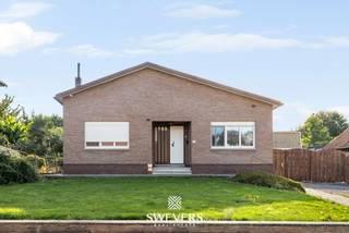 Voor meer info en foto’s, surf naar www.swevers.be – Vrijheerstraat 24 in Sint-Truiden biedt gelijkvloers wonen op een uitzonderlijk ruim perceel van 2.624 m². Deze open bebouwing uit 1968 ligt rustig en landelijk tussen Sint-Truiden en Heers, vlak bij de N3. De woning heeft een bewoonbare oppervlakte van 132 m², onderging al enkele opfrisbeurten maar heeft ruimte om verder naar eigen smaak te moderniseren. Via de centrale inkomhal bereik je de ruime leefruimte van 37 m² met plaats voor een comfortabele zit- en eethoek. Aansluitend bevindt zich de vernieuwde keuken van 11 m². Verder zijn er een badkamer met inloopdouche, een praktische berging en twee volwaardige slaapkamers van 12,60 m² en 14,40 m². Een zolder, bereikbaar via buiten, en een bijgebouw zorgen voor extra opslagruimte. De dubbele garage biedt plaats aan twee wagens. Een absolute troef is de grote, zuidwestelijk georiënteerde tuin. Dankzij de royale oppervlakte zijn er tal van mogelijkheden voor een terras, speelruimte, moestuin of groene ontspanningszones. Ook de ligging is praktisch: scholen bevinden zich op ca. 600 meter, openbaar vervoer op 800 meter, restaurants op 2 km en winkels op ongeveer 4 km. De snelweg (E40) ligt op circa 5,7 km. Een interessante woning voor wie ruimte, rust en gelijkvloers comfort zoekt en graag zelf verder vorm geeft aan zijn toekomstige thuis. Voor meer informatie, bel 011 255 155. Bron bewoonbare oppervlakte: EPC – verslag. Dit pand is onderworpen aan de renovatieverplichting van de Vlaamse overheid voor residentiële gebouwen (behoudens bij sloop binnen 5 jaar na de aankoop). Consulteer voor meer informatie de website van het Vlaams Energie- en Klimaatagentschap via https://www.vlaanderen.be/een-huis-of-appartement-kopen/renovatieverplichting-voor-residentiele-gebouwen.