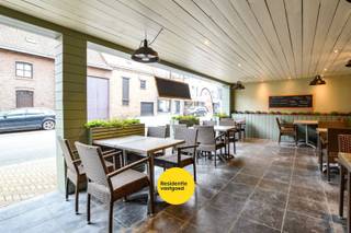 Deze ruime handelswoning in het centrum van Aartrijke combineert wonen en werken. Het handelspand beschikt over een volledig ingerichte keuken met aansluitend een ruime frigocel, ideaal voor horeca- of voedingsactiviteiten. Voor een vlotte logistieke werking is er een aparte doorgang voor leveranciers voorzien, zodat leveringen efficiënt kunnen gebeuren zonder de klantenruimte te storen. Daarnaast zijn er aparte toiletten voor de zaak.<br />Aan de handelsruimte bevindt zich een aangenaam overdekt terras met luifel, perfect om klanten in alle seizoenen een gezellige buitenruimte te bieden.<br /><br />Het woongedeelte bevindt zich eveneens op het gelijkvloers en biedt een comfortabele living met veel lichtinval. Op deze verdieping bevindt zich ook de slaapkamer evenals een zonnig binnenterras waar u in alle privacy kan genieten. Op de eerste verdieping vindt u de badkamer en twee bijkomende slaapkamers. <br /><br />Kortom, een veelzijdige handelswoning met praktische indeling en aangename woonruimtes.<br />EPC: energielabel C (Vg, Gmo, Wg, Gvkr, Gvv) Ref. OU28666<br /><br />Neem voorsprong met een vrijblijvende en gratis schatting van uw eigendom via:<br />www.residentievastgoed.be/gratisonlineschatten