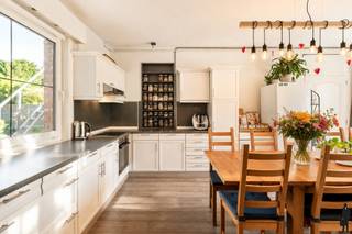 <strong>Karakteristieke en uitzonderlijk gelegen ingenieurswoning met o.a. 7 slaapkamers, 3 badkamers, hobbyruimte en private, organisch ingerichte natuurtuin. Het geheel ligt op een perceel van ca. 1.158m², rustig gelegen in één van de mooiste wijken te Mol, nabij de Nederlandse grens, Lommel, centrum-Mol en Balen. De woning van bouwjaar 1932 is volledig gerenoveerd en werd jarenlang deels als B&amp;B uitgebaat en deels gebruikt als woning. Het charmante geheel (van maar liefst 300m² bewoonbare oppervlakte) wordt thans in haar geheel voor bewoning benut maar kan eenvoudig terug worden omgevormd naar believen (kantoorruimte voor thuiswerk, B&amp;B, praktijkruimte (vrije beroeper), etc.). Nabij scholen, openbaar vervoer en op enkele minuten van Natuurpark Keiheuvel, Groendomein De Most en de natuur rond de Put van Rauw. EPC-score van 269kWh/m²/jaar (energielabel C). Dit betekent geen renovatieverplichting op grond van het Vlaamse Regeerakkoord. Ook de elektriciteit is volledig conform. Nabij Postel en Nederlandse grens.</strong><br />
<p><u>Gelijkvloerse verdieping:</u><strong><br /></strong>Via de inkomhal met vestiairegedeelte heeft u toegang tot de ruime woonkamer en de bijkeuken. De leefruimte met zithoek heeft een gezellige, nostalgische houtkachel. De leefruimte biedt verder toegang tot de bijkeuken en de lichtrijke hoofdkeuken met grote eettafel en toegang tot kelder op stahoogte. <br /><br />De ruime, lichtrijke keuken is geïnstalleerd met volgende kwaliteitstoestellen: o.a. vaatwasser (Miele), elektrische kookplaat (AEG), heteluchtoven (AEG) en voldoende kastruimte. Aan de keuken bevindt zich de benedenslaapkamer (B&amp;B-kamer 1) met douchemodule en afzonderlijke toilet.<br /><br />Aangrenzend aan de bijkeuken bevindt zich een gangruimte met koele berging en een tweede afzonderlijke toiletruimte.</p>
<p><u>Eerste verdieping</u><br />De authentieke, houten bordestrap in de inkomhal brengt u naar de eerste verdieping. Hier bevinden zich 4 ruime slaapkamers met veel lichtinval en tevens de hoofdbadkamer met inloopdouche, twee afzonderlijke wastafels en voldoende kastruimte. Er is een wasplaats voorzien. Eén van de vier slaapkamers wordt thans benut als massage- en therapieruimte. Een andere kamer doet dienst als B&amp;B-kamer 2. Laatstgenoemde kamers hebben beiden toegang tot een afzonderlijke badkamer met inloopdouche, wastafel en toilet.<br /><br /><u>Tweede verdieping</u><br />De tweede verdieping is opgedeeld in een 6de slaapkamer, een hobbyruimte (die momenteel dienst doet als muziekstudio) en een bergruimte. De hobbyruimte kan eenvoudig worden omgevormd tot 7de slaapkamer, bureau- of bibliotheekruimte.<br /><br /><u></u><u>Buitengebeuren</u><br />De woning heeft een oprit met poort aan de zijkant van de woning. Er is voldoende parking voor wagens. Achteraan in de tuin bevinden zich een drietal (stenen) bergruimten/tuinhuizen waarin allerlei (tuin)gereedschap kan worden opgeslaan. Het ruime terras geeft uit op de diepe, landelijke en private tuin. U vindt er verschillende kruidenperken, jonge heesters en bomen, plaats voor moestuin, alsook een sfeervolle vijverpartij met vis. De voor- (en achter)tuin kan naar believen worden aangelegd.<br /><br /><u>Bijzonderheden:<br /></u>- EPC van 269 kWh/m²/jaar: geen renovatieverplichting<br />- Bewoonbare oppervlakte van 300m² exclusief kelder<br />- Buitenschrijnwerk in hout en PVC, met overal dubbele beglazing<br />- Verwarming op gas (B&amp;B-deel), stookolie (woning-deel) en houtkachel<br />- Zeer gunstige ligging op wandelafstand van het centrum Wezel<br />- Mogelijkheid tot B&amp;B-uitbating (centrale ligging nabij Nederland en Postel)<br />- Vele andere mogelijkheden gelet op het aantal kamers en de beschikbare ruimte<br />- Voldoende parkeermogelijkheden<br />- Gezellige, authentieke ingenieurswoning ‘met een ziel’<br />- Mooie private en diepe natuurtuin: diverse mogelijkheden tot tuinaanleg</p>