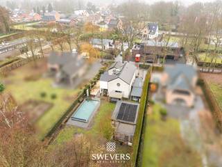Voor meer info en foto’s, surf naar www.swevers.be – Deze open bebouwing in Zonhoven, gebouwd in 2005 en tussen 2021 en 2025 grondig geoptimaliseerd, biedt instapklaar en energiezuinig wooncomfort. De woning beschikt over een zuidgericht perceel van 12 are 33 ca met een tuin van 713,98 m², een terras van 40 m² en een verwarmd zwembad op 21 zonnepanelen.<br />Binnen geniet u van een inkomhal met gastentoilet, een lichtrijke leefruimte van 34,43 m² met gashaard en directe toegang tot het terras, en een ruime keuken van 24,99 m² uitgerust met drie ovens, een stockageruimte en aparte zij-ingang. Verder is de woning volledig onderkelderd met natuurlijke lichtinval via lichtkoepels en ingericht met kelderberging, wasplaats, bureau en een atelier/mancave van 41 m².<br />Op de verdieping vindt u vier volwaardige slaapkamers (28,35 m², 20,59 m², 16,20 m² en 11,12 m²) met ingemaakte kasten, een badkamer met ligbad, dubbele wastafel en infraroodsauna, een aparte douchekamer en apart toilet.<br />Extra troeven zijn de dubbele carport, fietsenberging, vernieuwde zwembadinstallatie, airco’s, laadpaal, vernieuwde verwarmingsketel en versterkte elektriciteit, evenals een volledig uitgerust poolhouse met eigen ingang, living, keuken, badkamer en slaapkamer – ideaal als gastenverblijf of praktijkruimte.<br />Gelegen op 450 m van scholen en openbaar vervoer, 400 m van restaurants, 2,4 km van winkels en 5,4 km van de snelweg, nabij natuurgebied De Platwijers. Voor meer informatie, bel 011 255 155. Bron bewoonbare oppervlakte: EPC – verslag.