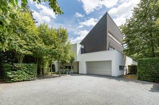 Deze ultra-moderne, energiezuinige villa (636 m² bewoonbare oppervlakte) heeft een strakke, witte kubusstructuur met metershoge glaswanden. Het pand beschikt over een EPC B-label, vloerverwarming (Viessmann), domotica, 24 zonnepanelen, leveren in totaal 9,8 kWp en een 12 kWh thuisbatterij.<br /><br />Gelegen op een perceel van ruim 20 are aan de Oude Baan in Essen. De tuin grenst aan agrarische velden, wat rust en privacy garandeert. Steden als Antwerpen en Breda liggen op 20 tot 30 minuten rijden. Natuurgebied de Kalmthoutse Heide bevindt zich dichtbij.<br /><br />Indeling:<br /><br />Gelijkvloers: Lichtrijke leefruimtes met een designhaard, een thuiskantoor met maatwerkkasten en een high-end leefkeuken met een groot werkeiland en luxe inbouwapparatuur.<br /><br />Verdiepingen: De eerste verdieping biedt een master bedroom met ensuite badkamer, plus twee slaapkamers en een tweede badkamer. De tweede verdieping telt nog twee slaapkamers en een derde badkamer.<br /><br />Kelder & Tuin: Een volledig onderkelderde ruimte, 200 m² aan casco ruimte (voor fitness, bioscoop, etc.). Er is alsook een inpandige garage voor 2 wagens. De strak aangelegde tuin heeft grote natuursteenterrassen en een beregeningsinstallatie.<br /><br />Bestuursmaatregelen in het maatregelenregister: nee