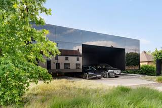 Deze uitzonderlijke nieuwbouwwoning, ontworpen door Binst Architects, is veel meer dan een woning, het is een krachtig architecturaal statement. Een strak paviljoenconcept vertaalt zich in een stijlvolle “black box” die zich bewust afzet tegen de omgeving en tegelijk volledig opgaat in het achterliggende landschap.<br /><br />De woning wordt gekenmerkt door een spel van contrasten: gesloten en open, licht en donker, privacy en transparantie. Zwartgelakt glas en gefumeerde beglazing zorgen voor een unieke, tijdloze uitstraling, terwijl grote glaspartijen overvloedig daglicht binnenbrengen en het zicht op de tuin en het zwembad maximaliseren.<br /><br />De leefruimte bevindt zich op de bovenverdieping en zweeft als het ware boven het terrein, met een panoramisch uitzicht op het omliggende groen. De slaapkamers zijn discreet geïntegreerd in een half ondergrondse verdieping, wat zorgt voor rust, privacy en een aangenaam binnenklimaat.<br /><br />Buiten wordt het architecturale verhaal doorgetrokken met een subliem afgewerkt overloopzwembad (infinity pool) dat visueel één wordt met het landschap, aangevuld met een stijlvol poolhouse. Hier ervaart u elke dag het gevoel van een exclusief privéresort.<br /><br />Troeven:<br />- Uniek ontwerp door Binst Architects<br />- Iconisch “black box” concept in zwartgelakt glas<br />- Infinity pool en luxueus poolhouse<br />- Maximale lichtinval en panoramisch uitzicht<br />- Doordachte indeling met gescheiden woon- en slaapniveau<br />- Absolute privacy en rust<br /><br />Deze woning laat zich niet vatten in woorden alleen: dit is een beleving.<br /><br />Bel ons voor meer informatie of een discreet bezoek.