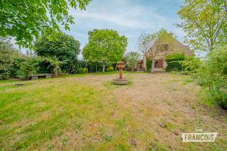 Een royale villa met karakter, privacy en tal van mogelijkheden, gelegen in een rustige residentiële omgeving van Oostduinkerke.<br /><br />Deze vrijstaande woning uit 1987 staat op een uitzonderlijk ruim perceel van 1.165 m² en beschikt over circa 319 m² bewoonbare oppervlakte. Met vier slaapkamers, een dubbele inpandige garage, een veranda, bureau, atelier en verschillende bergruimtes biedt de woning een bijzonder ruim en veelzijdig woonvolume.<br /><br />Bij binnenkomst leidt de inkomhal naar de verschillende leefruimtes. De royale woon- en eetkamer vormt het hart van de woning en sluit aan op de keuken en veranda. Dankzij de verschillende oriëntaties geniet de villa van een aangename natuurlijke lichtinval.<br /><br />Het gelijkvloers omvat daarnaast een bureau, atelier, stookruimte, toilet en een ruime dubbele garage. Ideaal voor wie thuis werkt, een hobbyruimte wenst of nood heeft aan extra bergruimte.<br /><br />Op de verdieping bevinden zich vier slaapkamers, een badkamer, dressing en een nachthal. Daarnaast is er een zolder van circa 40 m², momenteel ingericht als bergruimte.<br /><br />De woning wordt omringd door een ruime tuin en beschikt over een lange oprit, meerdere tuinhuizen en bijgebouwen. Er is dan ook voldoende plaats voor meerdere wagens en tal van buitenactiviteiten.<br /><br />De villa ligt in een aangename woonomgeving, op korte afstand van winkels, horeca, scholen, sport- en recreatiefaciliteiten, natuurgebieden en het strand.<br /><br />De woning verkeert momenteel in een op te frissen staat, waardoor u de verschillende ruimtes en afwerking naar eigen smaak kunt moderniseren.<br /><br />De villa beschikt over centrale verwarming op aardgas, een houtkachel en een regenwaterput van meer dan 10.000 liter. EPC-label C – 260 kWh/m²/jaar.<br /><br />