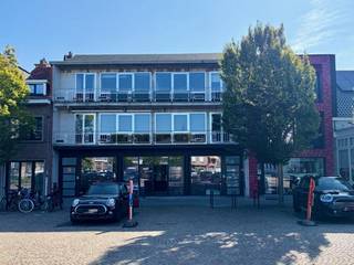 Op een uitstekende ligging in het centrum van Nijlen bevindt zich dit ruime gerenoveerde appartement met veel lichtinval, een zonnige leefruimte en een groot terras. Dankzij de centrale ligging geniet u van alle voorzieningen op wandelafstand en bovendien van een mooi zicht op de markt. Het appartement beschikt over een gunstig energielabel B en wordt verwarmd door middel van energiezuinige aircosystemen. Via de inkom en trap bereikt u de eerste verdieping, waarna enkele trappen toegang geven tot het appartement. Binnen komt u terecht in een ruime nachthal van circa 12 m². De bijzonder lichtrijke leefruimte van ongeveer 40 m² vormt samen met de moderne open keuken het hart van het appartement. De keuken is volledig ingericht en voorzien van een inductiekookplaat, koelkast, vaatwasser, dampkap en veel praktische kastruimte. Aan de voorzijde beschikt het appartement over een balkon met zicht op de markt, terwijl u aan de achterzijde kunt genieten van een groot terras van circa 20 m² met zuidoostelijke oriëntatie. Het appartement beschikt over twee slaapkamers. De eerste slaapkamer is circa 9 m². De tweede slaapkamer heeft een oppervlakte van circa 13 m². Alle ramen zijn voorzien van dubbele beglazing en vliegenramen. De badkamer van circa 7 m² is praktisch en comfortabel ingericht met een ligbad met douchescherm, een dubbele lavabo met spiegel en badkamermeubel, een toilet en ruimte voor een wasmachine en droogkast. Verder is er een berging met elektrische boiler van De Dietrich en beschikt het appartement over een videofoon. De combinatie van de ruime en zonnige leefruimte, twee slaapkamers, een gunstig B-label, een groot terras en de uitstekende ligging in het centrum van Nijlen maakt dit appartement bijzonder geschikt voor wie comfortabel en energiezuinig wil wonen op een centrale locatie. Voor info en bezichtiging: 0487/759.758 (STEEDS NA TELEFONISCHE AFSPRAAK)