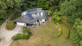 Architecturale villa in het groen, op een toplocatie in Heide<br /><br />Karaktervolle architectuur, royale leefruimtes, lichtinval en een oase van groen. Deze bijzondere villa in Heide combineert een uitgesproken architecturale uitstraling met een uitzonderlijk rustige ligging en een prachtige, volwassen tuin. En dat op behapbare afstand van het centrum, het treinstation, winkels en scholen én sportfaciliteiten.<br /><br />De woning valt meteen op door haar krachtige vorm, grote raampartijen en strakke tijdloze architectuur. Licht en ruimte spelen de hoofdrol, terwijl de leefruimtes op een natuurlijke manier in verbinding staan met de tuin. <br />Een woning met karakter, waar architectuur en natuur elkaar versterken.<br /><br />Rondom de villa ontvouwt zich een fraai aangelegde tuin met open ruimte, volwassen bomen, groene hagen en ruim terras. Hier geniet je in alle rust van het buitenleven, met volop privacy en het groen als decor.<br /><br />Gelijkvloers — ruimte, licht en connectie met de tuin<br />Via de inkomhal met vestiaire en gastentoilet kom je binnen in een woning waar ruimte en functionaliteit hand in hand gaan.<br />Ruim bureau met ingemaakte kasten en een aangenaam zicht op de tuin. Ideaal als thuiswerkplek of creatieve ruimte.<br />Lichtrijke leefruimte met parketvloer en een aparte, gezellige leeshoek. De grote raampartijen brengen het groen naar binnen en zorgen voor een directe verbinding met het zonnige terras.<br />Volledig ingerichte Bulthaup keuken (2009), royaal opgevat en uitgerust met kwalitatieve toestellen: een grote Miele-inductiekookplaat, oven, combi-oven, ingebouwde Miele-koffiemachine, vaatwasser, koelkast en diepvriezer.<br />Praktische bijkeuken met ingemaakte kasten en aansluitingen voor wasmachine en droogkast.<br /><br />Dubbele garage met automatische poort, met aansluitend toegang tot het overdekte terras.<br /><br />Kelderverdieping — extra ruimte en praktisch comfort<br />De ruime kelderverdieping biedt heel wat mogelijkheden en extra bergruimte. <br />Je vindt er verschillende stockageruimtes, een technische ruimte met de boiler, ingemaakte kasten en een aparte wijnkelder.<br /><br />Verdieping — vier slaapkamers en twee badkamers<br />Op de verdieping bevindt zich de master bedroom, een royale slaapkamer met dressing en rechtstreekse toegang tot het zonnige terras. <br />De aansluitende badkamer is uitgerust met een sauna, douche, toilet en dubbele lavabo.<br />Daarnaast zijn er drie volwaardige extra slaapkamers, waarvan één beschikt over bijkomende bergruimte achteraan. <br />Een tweede badkamer met douche en dubbele lavabo en een apart toilet vervolledigen deze verdieping.<br /><br />De tuin — groen, privacy en buitenleven<br />De tuin is zonder twijfel een van de grote troeven van deze woning. Het ruime gazon, de volwassen bomen en de groene hagen creëren een sfeervolle, beschutte omgeving waar rust en privacy centraal staan.<br />De zonnige terrassen bieden verschillende plekken om te genieten van lange zomeravonden of een rustig moment buiten. Een charmante siervijver en een praktisch tuinhuis maken het geheel compleet.<br /><br />Buitengewone kenmerken<br /><br />13 zonnepanelen, ongeveer 3 à 4 jaar oud<br />Thuisbatterij<br />Laadpaal voor een elektrische wagen<br />Dubbele garage met automatische poort<br />Zonnig overdekt terras<br />Fraai aangelegde tuin met volwassen groen en veel privacy<br />Alarmsysteem<br /><br />Mogelijkheid om het EPC-label te verbeteren: volgens de opgegeven informatie zou een lucht-luchtwarmtepomp (gecombineerd met de reeds aanwezige zonnepanelen en thuisbatterij) in de living, eetkamer en tv-hoek, met een COP van 4,0, kunnen bijdragen aan het behalen van een gunstiger EPC-label. <br /><br />Een architecturale villa voor wie houdt van karakter, licht en ruimte, met het comfort van vandaag en de rust van een groene omgeving. Een bijzonder aangename plek om thuis te komen, midden in Heide.