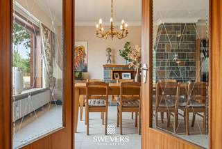 Voor meer info en foto’s, surf naar www.swevers.be – Aan de Schootstraat 128 in Heusden-Zolder vind je deze ruime open bebouwing op een zuidelijk georiënteerd perceel van 10a 85ca. De woning uit 1964 biedt 199 m² bewoonbare oppervlakte en vormt dankzij haar ruime indeling en renovatiemogelijkheden een interessante basis voor wie een gezinswoning volledig naar eigen smaak wil creëren. Op het gelijkvloers bevinden zich een centrale inkomhal, een living van 32 m², eetplaats, keuken van 16 m², badkamer, apart toilet en een extra woonkamer. Deze tweede leefruimte kan flexibel worden ingericht als bureau, hobbyruimte, slaapkamer of bijkomende zithoek. De woning telt vier slaapkamers van 34 m², 19 m², 18 m² en 11 m². Daarnaast is de woning grotendeels onderkelderd met onder meer een inpandige garage. Ook rolluiken zijn aanwezig. Het royale perceel met zuidelijke oriëntatie biedt volop mogelijkheden voor een aangename tuin en terras. De ligging combineert rust en groen met een goede bereikbaarheid. De Vallei van de Mangelbeek ligt op slechts 200 meter, openbaar vervoer op 50 meter en scholen en winkels op circa 550 meter. Ook de E313 en E314, Hasselt en Beringen zijn vlot bereikbaar. Een woning met veel ruimte, licht en potentieel voor wie grondig wil renoveren en een thuis op maat wil realiseren. Voor meer informatie, bel 011 255 155. Bron bewoonbare oppervlakte: EPC – verslag. Dit pand is onderworpen aan de renovatieverplichting van de Vlaamse overheid voor residentiële gebouwen (behoudens bij sloop binnen 5 jaar na de aankoop). Consulteer voor meer informatie de website van het Vlaams Energie- en Klimaatagentschap via https://www.vlaanderen.be/een-huis-of-appartement-kopen/renovatieverplichting-voor-residentiele-gebouwen.