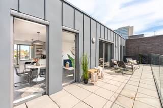 Deze instapklare penthouse is gelegen in de Lange Sint-Annastraat, een karaktervolle straat in het hart van Antwerpen, op het kruispunt van het Eilandje, de universiteitswijk en het historische centrum. Stijlvolle winkels, kwalitatieve horeca en culturele hotspots bevinden zich op wandelafstand, net als de Meir, Groenplaats en Grote Markt. Dankzij deze centrale ligging geniet u van het bruisende stadsleven, terwijl u bovenaan het gebouw in alle rust thuiskomt. Zowel openbaar vervoer als belangrijke invalswegen zijn vlot bereikbaar.<br /><br />Het appartement bevindt zich op de bovenste verdieping van een recente en verzorgde residentie. De lichtrijke leefruimte vormt het hart van het appartement en geeft via grote raampartijen toegang tot twee ruime zonneterrassen aan weerszijden. Dit zorgt de hele dag door voor overvloedig natuurlijk licht en een aangenaam panoramisch uitzicht over de stad. Aansluitend aan de leefruimte bevindt zich een aparte bureauruimte, ideaal als thuiswerkplek of in te richten als derde slaapkamer.<br /><br />De keuken is volledig uitgerust met kwalitatieve toestellen en een ruim werkblad, perfect voor wie graag kookt en gasten ontvangt. Verder beschikt het appartement over twee ruime slaapkamers, een modern afgewerkte badkamer met ligbad, inloopdouche en dubbel lavabomeubel, een apart gastentoilet en een praktische (was) berging. <br />Een privatieve kelderberging en gemeenschappelijke fietsenberging zijn inbegrepen. De aankoop van een ondergrondse autostaanplaats is mogelijk.