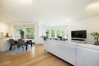 <p>Dit instapklare appartement op de eerste verdieping combineert ruimte, comfort en een hoogwaardige afwerking. <br />Via de inkomhal met vestiairekast bereikt u de lichtrijke leefruimte 30 m² op parket, voorzien van een stijlvolle boekenkast met geïntegreerde verlichting. <br />Aansluitend bevindt zich de volledig geïnstalleerde open keuken 15 m² met kwalitatieve Miele-toestellen en een composieten werkblad. <br />Vanuit de keuken heeft u via een schuifraam met vliegenraam toegang tot het overdekte terras.<br /><br />De nachthal geeft toegang tot een apart gastentoilet en de slaapvertrekken. <br />De ruime masterbedroom 30 m² beschikt over een dressing met maatwerkkasten en een ensuite badkamer met dubbele lavabo, inloopdouche, toilet en handdoekdroger. <br />De tweede slaapkamer 18 m² heeft eveneens een eigen douchekamer met lavabo.<br /><br />Verder beschikt het appartement over een praktische berging 5 m² met maatwerkkasten en aansluitingen voor wasmachine en droogkast, evenals een privatieve berging 7 m². Bij het appartement horen bovendien twee open autostaanplaatsen.<br /><br />BIJZONDERHEDEN<br />Vaste kosten 200 euro/maand.<br />Lift, vloerverwarming, CV op gas, Vaillant ketel, alarm, airco, rails voor kunst op te hangen, veiligheidsdeur.</p>