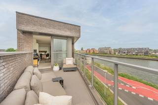 <p>Ontdek deze uitzonderlijk afgewerkte penthouse op een unieke locatie aan het water in Willebroek. Dankzij de grote raampartijen baadt het appartement de hele dag in natuurlijk licht en geniet u van een prachtig ruimtelijk gevoel.</p><p>Via de ruime inkomhal, voorzien van een stijlvolle ingebouwde vestiairekast, betreedt u deze luxueuze woonst. De lichtrijke leefruimte vormt het hart van de penthouse en geeft rechtstreeks uit op het royale, zuidgerichte terras waar u in alle rust kunt genieten van zon en uitzicht op het water. De leefruimte is afgewerkt met hoogwaardige parketvloeren, maatwerk kasten en een elegante ingebouwde gashaard die zorgt voor extra sfeer en comfort.</p><p>Aansluitend bevindt zich de open, volledig geïnstalleerde leefkeuken die naadloos overgaat in de woonruimte. Deze moderne keuken is uitgerust met kwalitatieve toestellen en beschikt bovendien over een geïntegreerde wijnkoeler, ideaal voor liefhebbers van gastronomie en gezelligheid.</p><p>De penthouse biedt twee volwaardige slaapkamers en een aparte walk-in dressing. De klasse volle badkamer is voorzien van een ligbad, ruime inloopdouche en een stijlvolle lavabo met hoogwaardig badkamermeubel.</p><p>Verder beschikt de woning over een praktische berging en een afzonderlijk gastentoilet.</p><p>Deze exclusieve penthouse combineert een toplocatie aan het water met een hoogwaardige afwerking, royale leefruimtes en een overvloed aan natuurlijk licht. Een unieke woonkans voor wie op zoek is naar comfort, luxe en uitstraling op een uitstekende locatie in Willebroek.</p><p></p><p>Het appartement is uiterlijk 1 december 2026 beschikbaar. <br />Stedenbouwkundige inlichtingen aangevraagd. </p><p>Dit pand wordt verkocht onder het stelsel van erfpacht. U koopt het appartement, kelderberging en autostaanplaats zelf, maar huurt de ondergrond. De canon (jaarlijkse vergoeding voor de grond) bedraagt +/- 1200€/jaar. Het erfpachtcontract loop tot en met 17/03/2107.</p>