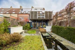 Deze smaakvolle bel-étagewoning is uitstekend gelegen op slechts 500 meter van de zeedijk van Heist en Duinbergen en vormt een ideale combinatie van ruimte, comfort en functionaliteit. Met een bewoonbare oppervlakte van maar liefst 384 m² biedt deze eigendom tal van mogelijkheden, gaande van een ruime gezinswoning tot een combinatie van wonen en werken of een oplossing voor zorgwonen, kangoeroewonen of cohousing.<br /><br />Bij het binnenkomen wordt U verwelkomd in een ruime inkomhal. Het gelijkvloers is bijzonder veelzijdig ingericht, met een uitzonderlijk diepe garage van ongeveer 15 meter waar twee wagens na elkaar kunnen parkeren. Daarnaast is er nog extra plaats voor fietsen, brommers en een bijkomende staanplaats voor de garagepoort. De garage is voorzien van ingemaakte kasten en beschikt bovendien over een aparte douche. Aansluitend bevindt zich een praktische was- en bergruimte met maatkasten tot aan het plafond langs beide zijden.<br /><br />Verder is er een volledig ingerichte studio op het gelijkvloers, uitgerust met een eigen douche en met rechtstreekse toegang tot de tuin. Dankzij de aparte inkom via de garage is deze ruimte perfect geschikt als praktijkruimte of als afzonderlijke wooneenheid.<br /><br />De onderhoudsvriendelijke tuin is zuidgericht en beschikt over meerdere terrassen, zodat U op elk moment van de dag van de zon kunt genieten. Achteraan geniet U van een open zicht, wat zorgt voor extra rust en privacy. Daarnaast is er een overdekt terras en een strak aangelegde vijver die het geheel compleet maken.<br /><br />Op de eerste verdieping bevindt zich een royale en lichtrijke leefruimte met een gezellige zit- en eethoek en een gashaard. De aansluitende leefkeuken biedt alle comfort en geeft uit op een aangename veranda waar het heerlijk vertoeven is tijdens het voor- en najaar. Verder is er nog een gastentoilet en een zonnig terras.<br /><br />De tweede verdieping omvat drie volwaardige slaapkamers, waarvan één met dressing, en een bijzonder ruime badkamer voorzien van ligbad, douche, dubbele wastafel en toilet.<br /><br />Tot slot is er nog een ingerichte zolderverdieping met twee extra kamers en een technische ruimte, ideaal als bijkomende slaapkamers, bureau of hobbyruimte.<br /><br />De woning beschikt over een goede energiescore (label B), zonnepanelen en een combinatie van verwarming op gas en warmtepomp, wat bijdraagt aan het energiezuinige karakter.<br /><br />Indeling:<br /><br />Gelijkvloers:<br />- Ruime inkomhal met vestiaire en gastentoilet,<br />- Zeer diepe garage (ca. 15 m) met plaats voor twee wagens,<br />- Extra staanplaats voor de garage,<br />- Ruimte voor fietsen en brommers met aparte toegang,<br />- Ingerichte garage met ingemaakte kasten,<br />- Afzonderlijke douche in de garage,<br />- Berging/wasplaats met maatkasten tot plafondhoogte,<br />- Volledig ingerichte studio met eigen douche,<br />- Rechtstreekse toegang tot de tuin,<br />- Zuidgerichte, onderhoudsvriendelijke tuin,<br />- Overdekt terras en aangelegde vijver,<br />- Meerdere zonneterrassen met open zicht achteraan,<br /><br />Eerste verdieping:<br />- Hal met gastentoilet,<br />- Royale leefruimte met zit- en eethoek,<br />- Bergruimte,<br />- Volledig ingerichte leefkeuken,<br />- Aansluitende veranda,<br />- Zonneterras,<br /><br />Tweede verdieping:<br />- Nachthal,<br />- Drie slaapkamers,<br />- Dressing bij één van de slaapkamers,<br />- Zeer ruime badkamer met ligbad, douche, dubbele wastafel en toilet,<br /><br />Zolderverdieping:<br />- Twee extra kamers,<br />- Technische ruimte,<br /><br />Bent U op zoek naar een uitzonderlijk ruime en instapklare woning met tal van mogelijkheden op een topligging aan de kust? Dan is dit zonder twijfel een unieke kans. Neem vandaag nog contact op voor een bezoek en ontdek zelf de troeven van deze veelzijdige eigendom!