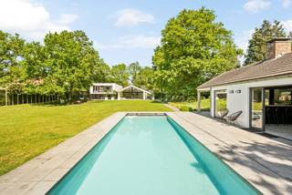Discover this exceptional villa, beautifully located in the green and sought-after area of Oud-Turnhout. This unique property was completely renovated and (partially) rebuilt in 2018 in collaboration with AIM architects, seamlessly combining luxury, comfort, and contemporary architecture. The location of the villa in Oud-Turnhout also offers many advantages. It is a quiet and green area, ideal for those seeking a peaceful oasis in nature. At the same time, all amenities such as shops and schools are easily accessible at a short distance.<br /><br />Situated on a generous plot of 3,937 m², you can enjoy absolute tranquility, optimal privacy, and breathtaking views over the surrounding meadows. The impressive living area of 553 m² offers plenty of space for comfortable living, working, and relaxing.<br /><br />Thanks to the thoughtful architecture and large windows, every living space is flooded with natural light. The property is fully connected to the beautifully landscaped garden and the expansive landscape behind it, creating a seamless transition between indoor and outdoor living. At the front, you also enjoy complete discretion, adding to the exclusive character of this property.<br /><br />Through the imposing, pivoting front door, you enter the stylish entrance hall, setting the tone for the rest of the house. From here, the spectacular living space opens up, where abundant natural light, impressive ceiling heights, and thoughtful architecture create an exceptional feeling of space and elegance.<br /><br />The luxurious kitchen, made of high-quality Corian, is undoubtedly the heart of the home. It is equipped with a fully integrated package of Miele appliances, including various ovens, a steamer, warming drawers, refrigerator, dishwasher, Quooker, and induction hob. The spacious, extendable Corian dining table invites long, cozy dinners with family and friends.<br /><br />Adjacent is a cozy sitting area with a stylish bar, where the large windows offer a beautiful view of the garden. Thanks to the wide sliding doors, indoor and outdoor living seamlessly blend together and provide direct access to the sunny terraces. The bar also provides the ideal setting for entertaining guests in style for an aperitif or a cozy evening.<br /><br />On the ground floor, there is also a second lounge or TV room with a beautiful see-through fireplace to the living room, a fully equipped fitness room, and an open office or workspace. From the entrance hall, you also reach a separate office with an adjoining wellness area, equipped with a sauna, shower, and toilet. This area also offers the possibility of being easily converted into a ground floor bedroom with an en-suite bathroom, making the property perfectly suitable for lifelong living.<br /><br />Finally, the ground floor features a practical laundry room with custom-made cabinets and a separate side entrance, additional storage space, a double indoor garage, and a spacious guest toilet. A ground floor that excels in space, functionality, and refined luxury, designed for optimal living comfort and a unique living experience.<br /><br />Through a secure door, you reach the staircase hall that gives access to the upper floor, fully furnished with comfort, privacy, and luxury in mind. Here are three spacious children's bedrooms, each equipped with practical custom-made wardrobes. These rooms share a stylish bathroom, equipped with a double sink in a sleek design furniture piece, a spacious walk-in shower finished with refined mosaic tiles, and a separate toilet.<br /><br />The exclusive master suite is without a doubt the absolute showpiece of this floor. This private wing has a spacious dressing room, a large bedroom, and a luxurious en-suite bathroom with a freestanding bathtub, an exceptionally large walk-in shower, and an elegant bathroom furniture piece with a sink. Thanks to the impressive windows, you can enjoy a panoramic view of the beautifully landscaped garden and the surrounding meadows every morning.<br /><br />The beautifully landscaped garden is perfectly oriented to the southwest, allowing you to enjoy optimal sunlight throughout the day. At the back of the garden is an impressive pool house that is fully furnished for relaxation and entertainment. The covered terrace, equipped with electric heaters, allows you to comfortably enjoy outdoor living in every season. The stylish outdoor bar and kitchen are equipped with all necessary facilities, including two refrigerators, a freezer, a sink, and a high-quality built-in Boretti gas barbecue with professional extraction.<br /><br />Inside, the pool house has a cozy lounge and dining area with air conditioning, making it a full-fledged additional living space for long summer evenings and cozy receptions with family and friends. The annex also includes a practical changing room with a shower and toilet, as well as a technical room and storage.<br /><br />Next to the pool house in the garden is the heated swimming pool, measuring an impressive 11 x 5 meters, equipped with high-quality techniques such as an automatic pool cover and an electrolysis system for optimal ease of use and simple maintenance. The spacious sun terrace is the perfect place to relax and is enhanced by integrated, weather-resistant Bose sound speakers, providing an exclusive atmosphere.<br /><br />An exceptional outdoor environment where luxury, comfort