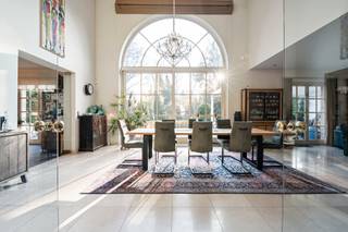 Deze uitzonderlijk ruime Amerikaanse luxevilla, gelegen op wandelafstand van het centrum van Heide, biedt een zeldzame opportuniteit voor de zelfstandige ondernemer of het een gezin op zoek naar ruimte, comfort en kwaliteit.<br /><br />De villa verkeert in uitstekende staat en werd met oog voor detail afgewerkt met hoogwaardige materialen door de hele woning.<br />Men betreedt de woning via een grote inkomhal op natuursteen, met een vestiare ruimte leidt tot en een gastentoilet met lavabo. De lichtrijke leefruimte, eveneens op natuursteen, omvat een elegante zithoek en een eetkamer, gescheiden door een sfeervol tweezijdige gashaard. Een tweede zithoek op parket vervolledigt dit warme geheel — de ideale plek voor het gezin om samen te komen.<br /><br />Aansluitend aan de eetkamer bevindt zich de volledig uitgeruste keuken met alle toestellen en zicht op de tuin. Dankzij haar royale afmetingen biedt de keuken bovendien ruimte voor een gezellige eettafel — het kloppend hart van de woning.<br /><br />Op het gelijkvloers is verder een ruime slaapkamer op parket met ensuite badkamer (douche, lavabo en toilet), een praktische zijdeur en toegang tot de kelder. en naar de tuin . Deze kamer leent zich uitstekend als gastenkamer of au-pair verblijf.<br /><br />De trap in de inkomhal leidt naar de eerste verdieping, waar een spectaculaire, lichtrijke overloop met mezzaninegevoel boven de eetkamer de verdieping bepaalt — ideaal als extra zithoek, speelruimte of thuiskantoor. Op deze verdieping bevinden zich drie slaapkamers, elk voorzien van airconditioning, en een gedeelde badkamer met ligbad, douche, lavabo en toilet.<br /><br />De hoofdslaapkamer beschikt over een luxueuze ensuite badkamer met jacuzzi ligbad, douche en dubbele lavabo, en grenst aan een royale inloopdressing met ingebouwde kasten en Laden .<br /><br />Via een vaste trap bereikt men de zeer ruime zolder, momenteel ingericht als kantoor. Achter een wand bevindt zich bovendien een grote bergzolder met bijkomend integratiepotentieel — of extra speelruimte voor de kinderen.<br /><br />De volledige kelderverdieping van ca. 200 m² herbergt een technische ruimte, werkplaats, wasruimte, extra berging én een sport ruimte plus een indrukwekkende garage met plaats voor meerdere wagens.<br /><br />De villa is gelegen op een prachtig, zuidgericht open perceel. De tuin beschikt over een deels overdekt terras met zicht op een sierlijke vijver, een verwarmd zwembad met automatische overkapping en een tuinhuis met extra opslagruimte.<br /><br />Deze villa ligt langs een mooie laan in Heide-Kalmthout. Het gezellige centrum ligt op wandelafstand, met alle nodige voorzieningen binnen handbereik. Het station biedt een vlotte verbinding naar Antwerpen, Brussel en Nederland.