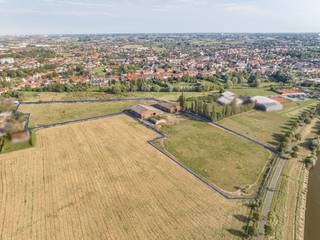 Exclusieve Kans in het Hart van de Leievallei! Wij presenteren met trots deze uitzonderlijke landelijke eigendom, gelegen aan de Bondgenotenlaan en de Leie in Kuurne. Met een totale grondoppervlakte net geen 4 hectare (39.924 m²), biedt dit unieke pand een zeldzame combinatie van natuur, ruimte en mogelijkheden. De eigendom grenst aan de Leie en het jaagpad, en kijkt uit op de prachtige Heulebeekvallei, wat zorgt voor een ongeëvenaard uitzicht en een rustige, landelijke sfeer.<br />sfeerfilm: https://youtu.be/U5SBKlvnXKY<br /><br />Strategische Ligging en Bereikbaarheid. <br />De locatie van deze eigendom is ongeëvenaard. Gelegen op de overgang tussen het natte valleilandschap van het waterpark en de open ruimte van de Leiemeersen, biedt het zowel privacy als directe toegang tot de natuurlijke schoonheid van de regio. Toch bent u slechts enkele minuten verwijderd van het centrum van Kuurne en belangrijke verbindingswegen, waardoor steden zoals Kortrijk en Harelbeke snel bereikbaar zijn. Dit maakt het pand ideaal voor wie rust en het landelijke zoekt zonder in te boeten op bereikbaarheid.<br /><br />Veelzijdige Bestemmingsmogelijkheden<br />De eigendom valt onder het BPA (Bijzonder Plan van Aanleg) dat als hoofdbestemming oa recreatie, sport en gemeenschapsvoorzieningen voorschrijft. Daarnaast zijn ook wonen en horeca als nevenfunctie mogelijk. Deze veelzijdigheid opent tal van mogelijkheden.<br />Momenteel is er op het terrein een paardenmanège, wat aangeeft dat de locatie al geschikt is voor activiteiten die harmonieus samengaan met de natuurlijke omgeving. Daarenboven zijn er 3 ruime hangars aanwezig op het terrein die beschikken over royale volumes en zijn voorzien van meerdere stallingen alsook een ruime binnenpiste.<br /><br />Onderdeel van het Masterplan 'Vlaspark'<br />Deze eigendom maakt deel uit van het ambitieuze masterplan 'Vlaspark', dat gericht is op de ontwikkeling van een duurzaam en geïntegreerd landschap. De strategische ligging op de overgang tussen het waterpark en de Leiemeersen onderstreept de waarde van deze site binnen het bredere regionale plan. Investeren in deze eigendom betekent deel uitmaken van een toekomstgerichte visie voor Kuurne en omstreken.<br /><br />Kortom, deze landelijke eigendom biedt een zeldzame kans om te investeren in een uitzonderlijk vastgoed met ongekende mogelijkheden. Of u nu een visionair project wilt ontwikkelen, een oase van rust zoekt of een strategisch gelegen commerciële exploitatie overweegt, deze locatie heeft het allemaal.<br /><br />Neem contact met ons op voor meer informatie of om een bezichtiging in te plannen. Dit is een kans die u niet wilt missen!<br /><br />Onze ref. DEV5124