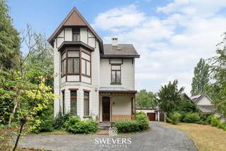 Voor meer info en foto’s, surf naar www.swevers.be – Aan de Koolmijnlaan 190 in Koersel vindt u deze karaktervolle vrijstaande herenwoning uit 1918. Met 331 m² bewoonbare oppervlakte, hoge plafonds, authentieke elementen en royale ruimtes biedt deze te renoveren woning bijzonder veel potentieel. De gelijkvloerse verdieping omvat een centrale inkomhal, woonkamer met erker, afzonderlijke leef- en eetruimte, keuken, tweede hal, toilet en berging. De bestaande indeling biedt volop mogelijkheden om de woning tijdens de renovatie aan te passen aan een hedendaagse woonstijl. Op de eerste verdieping bevinden zich vier ruime slaapkamers en een badkamer. De tweede verdieping telt nog drie slaapkamers, waardoor de woning in totaal zeven ruime slaapkamers biedt. Ideaal voor een groot gezin, thuiswerk of hobby- en logeerruimtes. Daarnaast is er een ruime kelder van circa 85 m². Via de oprit bereikt u twee grote garages. Achteraan ligt een royale, zuidwest georiënteerde tuin met zwembad op een perceel van bijna 20 are. Verder zijn onder meer zonnepanelen, elektrische rolluiken en een alarmsysteem aanwezig. Scholen, openbaar vervoer en restaurants liggen vlakbij. Ook winkels, ontspanning, de snelweg en be-MINE zijn vlot bereikbaar. Een unieke kans voor wie karakter, ruimte en renovatiepotentieel wil combineren. Voor meer informatie, bel 011 255 155. Bron bewoonbare oppervlakte: EPC – verslag. Dit pand is onderworpen aan de renovatieverplichting van de Vlaamse overheid voor residentiële gebouwen (behoudens bij sloop binnen 5 jaar na de aankoop). Consulteer voor meer informatie de website van het Vlaams Energie- en Klimaatagentschap via https://www.vlaanderen.be/een-huis-of-appartement-kopen/renovatieverplichting-voor-residentiele-gebouwen.