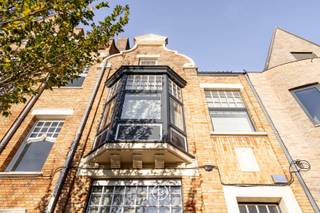 Op een topligging langs de Komvest, op wandel- en fietsafstand van het bruisende centrum van Brugge, bevindt zich deze uitzonderlijk ruime en lichtrijke woning. In de onmiddellijke nabijheid van scholen, winkels en ontspanning combineert ze het beste van stadsleven met ruimte en rust.<br /><br />Dankzij haar volume en indeling is deze woning ideaal voor wie wonen en werken wil combineren. In 1994 onderging het pand een grondige totaalrenovatie. In 2003 werd bovendien het naastliggende pand als nieuwbouw geïntegreerd in de woning, waardoor een bijzonder ruim en harmonieus geheel ontstond. <br /><br />Het souterrain biedt verschillende polyvalente ruimtes met burelen, ideaal voor het uitoefenen van een vrij beroep. Op de bel-etage vindt u twee leefruimtes, twee volledig uitgeruste keukens en toegang tot een ruim zonneterras. De verdiepingen tellen in totaal zes slaapkamers en vier badkamers. <br /><br />De zuidwestgerichte stadstuin met meerdere terrassen biedt optimale privacy. Achteraan, via de Werfstraat, bevindt zich een ruime achterbouw met dubbele garage met laadpaal en veranda. De casco-ruimte op de verdieping kan, dankzij voorziene aansluitingen, perfect ingericht worden als studio.<br /><br />Kortom, een unieke eigendom met tal van mogelijkheden zoals het uitoefenen van een vrij beroep, een kangoeroewoning of een B&amp;B.