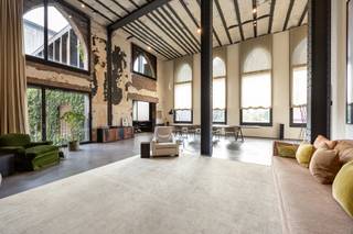 Op de historische Kanaalsite in Wijnegem, een voormalige graanstokerij uit 1857 langs het Albertkanaal, bevindt zich deze buitengewone penthouse van circa 330 m², eigenhandig ingericht door Axel Vervoordt.<br /><br /><span>Indeling:</span><br />De imposante leefruimte heeft een plafondhoogte van maar liefst 6,16m, gedragen door authentieke zwarte stalen kolommen en balken en met karakteristieke rondboogramen. De authentieke, verweerde muren en de strakke gietvloer benadrukken het industriële karakter en versterken het zeer openlijk ruimtegevoel.<br /><br />Onder de mezzanine bevindt zich de stijlvolle leefkeuken met bijkeuken. De keuken is uitgerust met donker houten maatwerkkasten met ingebouwde koffiecorner, een robuust kookeiland en een La Cornue-fornuis. De Vola-armaturen en de authentieke wandtegels versterken de tijdloze, pure uitstraling. <br /><br />Deze loft telt drie ruime slaapkamers, verdeeld over de eerste verdieping (één slaapkamer) en de tweede verdieping (twee slaapkamers). <br /><br />Blikvanger is de master bedroom op de vide, met een indrukwekkend uitzicht op de leefruimte. Deze master bedroom is uitgerust met een royale dressing, een en-suite badkamer en is ook gemakkelijk bereikbaar via de lift.<br /><br />De tweede slaapkamer dient momenteel als fitnessruimte en beschikt over een badkamer met douche. Eveneens rechtstreekse toegang tot het terras.<br /><br />De derde slaapkamer bevindt zich op het gelijkvloers, samen met de derde badkamer, met ligbad en dubbele wastafel.<br /><br />Ruim overdekt terras met open zicht.<br /><br />Inclusief 3 staanplaatsen en berging.<br /><br /><span>Bijzonderheden:</span><br />Gebruik van duurzame en hoogwaardige materialen - vloerverwarming op aardgas, domotica , stalen ramen, hoogrendementsglas, ventilatiesysteem, hoge plafonds en binnendeuren, gepolierde betonvloer, videofoon <br />Gemeenschappelijke kosten ca. 400 euro per maand (blokpolis, syndicus, onderhoud gemene delen, tuinonderhoud met snoeiplan) <br /><br />EPC label B - 166 kWh/m² - UC 2555207 - elektr. conform<br /><br />Vg-Wg-Gvv-Gvkr-Gmo-Gworg
