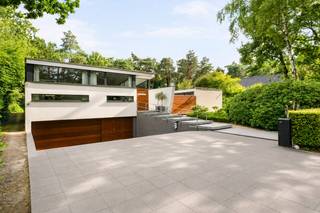 Op een absolute toplocatie in het groene Poppel, verscholen in een rustige residentiële omgeving en grenzend aan de natuur, bevindt zich deze uitzonderlijke architecturale villa. Een eigendom waar luxe, privacy, ruimte en verfijning op harmonieuze wijze samenkomen. Dankzij de doordachte architectuur, hoogwaardige materialen en de naadloze verbinding tussen binnen- en buitenruimtes geniet u hier elke dag van een exclusieve woonbeleving.<br /><br />Bij het betreden van de woning wordt u verwelkomd in een inkomhal met vestiaire en een apart gastentoilet. Vanuit deze royale entree bereikt u zowel de leefruimtes als, via een stijlvolle glazen doorgang, de afzonderlijke slaapvleugel.<br /><br />De bijzonder lichtrijke leefruimte vormt het hart van de woning. Grote glaspartijen brengen het omliggende groen naar binnen en creëren een unieke interactie tussen de woning, de Japanse binnentuin en het zwembad. De sfeervolle gashaard zorgt voor warmte en gezelligheid, terwijl één van de raampartijen is uitgevoerd in innovatief schakelbaar glas voor extra comfort op zonnige dagen.<br /><br />De hypermoderne leefkeuken werd in 2023 verder geoptimaliseerd met een Liebherr Fresh-koelkast, Siemens inductiekookplaat en combi-oven, een Miele vaatwasser en een Quooker. De maatwerkkasten en de praktische bijkeuken maken het geheel compleet.<br /><br />Ook het souterrain werd ingericht met oog voor ontspanning en functionaliteit. Hier bevinden zich een ruime homecinema, een volledig ingerichte fitnessruimte, een technische ruimte en een royale inpandige garage voor twee wagens. Indien gewenst kan de fitnessruimte opnieuw bij de garage worden betrokken, waardoor plaats ontstaat voor een derde wagen. Daarnaast beschikt de woning over parkeergelegenheid voor maar liefst negen bezoekerswagens.<br /><br />Via de volledig beglaasde doorgang, met zicht op de sfeervol verlichte Japanse binnentuin, bereikt u de slaapvleugel. De master suite beschikt over een royale slaapkamer en een smaakvol vernieuwde badkamer (2019), uitgerust met een ligbad, dubbele wastafel en een exclusieve Sunshower met keuze tussen infraroodwarmte of UV-licht.<br /><br />Daarnaast zijn er nog twee ruime slaapkamers en een tweede badkamer, die in 2025 volledig werd vernieuwd. De aansluitende wellnessruimte beschikt over een sauna voor zes personen met zowel een traditionele saunakachel als een infraroodfunctie. Een praktische wasplaats vervolledigt deze vleugel.<br /><br />Ook buiten werd werkelijk aan alles gedacht. Het ruime overdekte terras vormt een natuurlijk verlengstuk van de leefruimte en kijkt uit over de prachtig aangelegde tuin en het verwarmde zwembad. Dankzij het vernieuwde solardek warmt het zwembadwater tijdens zonnige dagen op tot ongeveer 29,5°C, terwijl een automatische zwembadrobot instaat voor het onderhoud.<br /><br />De Japanse binnentuin vormt het architecturale middelpunt van de woning en wordt 's avonds sfeervol verlicht. Dankzij een geïntegreerd drainagesysteem en een automatische druppelirrigatie blijft deze tuin het hele jaar door perfect onderhouden. Ook de voor- en achtertuin beschikken over een geautomatiseerd RainBird-beregeningssysteem met WiFi-bediening, gevoed via een geslagen waterput.<br /><br />Achteraan op het perceel, discreet verscholen tussen het groen maar volledig op eigen terrein, bevindt zich een tuinhuis van ca. 18 m², voorzien van elektriciteit en verlichting.<br /><br />Ook op technisch vlak voldoet deze villa aan de hoogste verwachtingen. Zo beschikt de woning over 28 zonnepanelen (11 kW), een Alfen Pro-laadpaal, automatische screens aan de glazen gang, master bedroom en het overdekte terras, een professioneel alarm- en camerabewakingssysteem en een gunstig EPC-label B.<br /><br />Deze uitzonderlijke villa biedt een zeldzame combinatie van architectuur, luxe, comfort, technologie en privacy op een unieke locatie midden in het groen. Een exclusieve woonbeleving voor wie enkel genoegen neemt met het allerbeste.<br /><br />Bijzonderheden<br />*Absolute topligging in een rustige, residentiële omgeving grenzend aan de natuur<br />*Vernieuwde leefkeuken (2023) met hoogwaardige Siemens-, Miele-, Liebherr- en Quooker-uitrusting<br />*Homecinema, fitnessruimte en inpandige garage voor 2 à 3 wagens<br />*Luxueuze masterbedroom met een ensuite badkamer, uitgerust met een Sunshower.<br />*Tweede badkamer volledig vernieuwd in 2025<br />*Wellnessruimte met sauna voor 6 personen (traditioneel & infrarood)<br />*Verwarmd zwembad met vernieuwd solardek en automatische zwembadrobot<br />*Geautomatiseerde screens en RainBird-beregeningssysteem<br />*Professioneel alarm- en camerabewakingssysteem<br />*28 zonnepanelen (11 kW) en Alfen Pro-laadpaal<br /><br />Uitstekende verbinding richting Nederland en omliggende gemeenten.