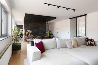 Gelegen op de vierde verdieping en bereikbaar via de lift, betreedt men dit appartement via een verzorgde inkomhal. Deze geeft uit op een ruime leef- en eetruimte met eiken parket. Dankzij de brede gevel en de grote raampartijen geniet de ruimte van veel natuurlijke lichtinval.

Aansluitend bevindt zich de open keuken, visueel gescheiden van de leefruimte door een wand. Zowel de keuken als de inkomhal zijn afgewerkt met een nieuwe beton ciré-vloer. De keuken werd volledig vernieuwd en beschikt over een groot keukeneiland met veel werk- en opbergruimte. De keuken is uitgerust met kwalitatieve toestellen, waaronder een AEG-inductiekookplaat, vaatwasser, combi-oven tot 250°C met zelfreiniging, een Amerikaanse koelkast en een Quooker-kraan. Het werkblad is uitgevoerd in keramiek met travertinlook. Op deze verdieping bevinden zich verder nog een apart gastentoilet en een praktische berging.

Via de trap bereikt men de bovenverdieping. Deze geeft uit op een ruim, zuidwestgericht zonneterras met zicht op het MAS. Op deze verdieping bevinden zich twee slaapkamers, waaronder een ruime masterbedroom met aansluitende dressing, voorzien van maatkasten. Beide slaapkamers zijn uitgerust met airconditioning.

De vernieuwde badkamer beschikt over een inloopdouche, een vrijstaand bad en waskommen in solid surface-materiaal.

Tot slot is er de mogelijkheid om een ondergrondse autostaanplaats aan te kopen, niet inbegrepen in de vraagprijs.