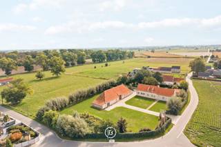 Deze karaktervolle fermette in Gistel bevindt zich op een ruim perceel van 5.202 m² en combineert een solide woning met een grote, veelzijdige schuur. Het hoofdhuis werd gebouwd in 2010 en vormt vandaag een uitstekende basis voor wie de eigendom verder naar eigen smaak wil afwerken en moderniseren.<br /><br />Hoewel het interieur op bepaalde vlakken een update kan gebruiken, werd bij de bouw gekozen voor kwalitatieve en duurzame materialen. Zo beschikt de woning onder meer over volle eiken parketvloeren en deuren en een bijzonder stevige constructie. Op het gelijkvloers bevinden zich de inkomhal met gastentoilet, living, eetruimte, veranda, keuken, mudroom/bijkeuken, badkamer en een slaapkamer.<br /><br />De verdieping is momenteel één grote open ruimte en biedt daardoor bijzonder veel potentieel. Met een doordacht ontwerp kunnen hier eenvoudig meerdere bijkomende slaapkamers en één of meerdere badkamers worden gerealiseerd. De oppervlakte laat minstens twee bijkomende slaapkamers toe, maar biedt voldoende ruimte om desgewenst tot vier kamers op deze verdieping te creëren. Hierdoor kan de woning volledig worden afgestemd op de noden van de toekomstige eigenaar.<br /><br />Een bijkomende troef is de grote vrijstaande schuur. Ook deze werd aan de buitenzijde vernieuwd, met onder meer een nieuw dak en vernieuwde muren. De ruimte kan vandaag dienstdoen als ruime garage of opslagplaats, maar biedt eveneens interessant toekomstpotentieel als bureel of praktijkruimte.<br /><br />Buiten sluit een zuidgericht terras aan op de woning, waar dankzij de ligging ook ’s avonds nog van de zon kan worden genoten. Alle aanwezige gebouwen en verhardingen zijn vergund.<br /><br />Een eigendom met een sterke basis, kwalitatieve materialen en vooral veel mogelijkheden voor wie op zoek is naar ruimte en flexibiliteit en de laatste afwerking graag naar eigen hand zet.