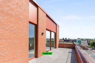In het stijlvolle nieuwbouwproject Eilandpark te Sint-Lievens-Houtem, op wandelafstand van het centrum, bevindt zich deze exclusieve en hoogwaardig afgewerkte penthouse. Dankzij de combinatie van ruimte, lichtinval, duurzame materialen en hedendaags wooncomfort vormt deze eigendom een unieke opportuniteit voor wie op zoek is naar luxueus wonen op een rustige doch centrale locatie. Bij het betreden van de penthouse komt u terecht in de ruime inkomhal, waar voldoende plaats voorzien is voor een vestiaire. Verder beschikt de inkomhal over een gastentoilet en geeft deze toegang tot de verschillende leefruimtes. De zon- en lichtovergoten leefruimte vormt zonder twijfel het hart van het appartement. Dankzij de grote raampartijen geniet u hier van een uitzonderlijk ruimtegevoel en een overvloed aan natuurlijk licht. De open keuken sluit naadloos aan op de leefruimte en werd afgewerkt met duurzame en kwalitatieve materialen, volledig in lijn met het luxueuze karakter van de penthouse. Het ruime terras vormt een directe verlenging van de leefruimte en creëert een aangename buitenbeleving waar u in alle rust kan genieten van de zon en het open gevoel. Verder beschikt de penthouse over twee volwaardige slaapkamers, een ruim ingerichte badkamer, een praktische technische berging en een afzonderlijke stockageberging, wat zorgt voor extra comfort en opslagmogelijkheden. De penthouse wordt bovendien volledig geschilderd en voorzien van gordijnen, waardoor deze quasi instapklaar wordt opgeleverd. Ook op technisch vlak voldoet deze eigendom aan alle hedendaagse normen en technieken, wat resulteert in energiezuinig en toekomstgericht wonen. Bij de penthouse dient verplicht een ondergrondse autostaanplaats aangekocht te worden.<br /><br />De prijs wordt opgesplitst in een grondwaarde (onderhevig aan registratierechten) en een constructiewaarde (onderhevig aan 21% btw). De vermelde prijs is exclusief aankoopkosten en exclusief de aankoop van de parkeerplaats.<br /><br />Deze exclusieve penthouse combineert luxueus wooncomfort, hoogwaardige afwerking en een uitstekende ligging, en vormt daardoor een absolute topper binnen het project Eilandpark<br /><br />