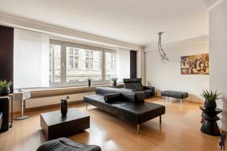 Gelegen in de Bourlastraat, één van de meest gegeerde straten in het historische centrum van Antwerpen, bevindt zich dit uitzonderlijk ruime appartement op de tweede verdieping van een verzorgd gebouw met lift.<br /><br />U woont hier recht tegenover de Nationale Bank, omringd door statige architectuur, kwalitatieve horecazaken en winkels. Alles ligt op wandelafstand, waardoor u geniet van het bruisende stadsleven met maximaal comfort.<br /><br />Het gebouw is zeer goed onderhouden. Het dak en de lift zijn vernieuwd en er zijn geen grote kosten gepland.<br /><br />Indeling<br /><br />Via de lift bereikt u het appartement op de tweede verdieping. Bij het binnenkomen valt meteen het aangename ruimtegevoel op, dankzij de hoge plafonds en brede gevel. De uitzonderlijk ruime leefruimte is zuidgericht en geniet van veel natuurlijk licht. Bovendien is de leefruimte voorzien van airconditioning.<br /><br />De volledig uitgeruste keuken beschikt over bijzonder veel kastruimte en werkoppervlak. Ze is goed onderhouden en biedt mogelijkheden voor wie graag een eigen, hedendaagse toets toevoegt. Vanuit de keuken is er toegang tot een klein terras.<br /><br />Verder zijn er twee zeer ruime slaapkamers. De master bedroom bevindt zich aan de achterzijde en geniet van optimale rust. De tweede slaapkamer is eveneens een ruime, volwaardige slaapkamer.<br /><br />Extra troeven: <br />Zuidgerichte leefruimte,<br />Hoge plafonds<br />Airconditioning in de leefruimte<br />EPC B<br />Goed onderhouden gebouw <br />Kelderberging aanwezig