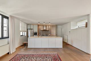 Op de vierde verdieping van een zeer goed onderhouden gebouw bevindt zich dit lichtrijke en instapklare appartement van ca. 125 m², gelegen in de Molenstraat. Dankzij de uitzonderlijk brede gevel geniet het appartement van veel natuurlijke lichtinval en een aangenaam ruimtegevoel.<br /><br />Bij het betreden van het appartement komt u in de inkomhal met apart gastentoilet. Van hieruit bereikt u de ruime leefruimte met open keuken. De grote raampartijen zorgen voor een open en luchtig gevoel en geven rechtstreeks toegang tot het eerste zuidgerichte terras met uitzicht op de binnentuin.<br /><br />De open keuken werd vernieuwd en is praktisch ingericht, met aansluitend een berging met aansluiting voor wasmachine en droogkast.<br /><br />Via de nachthal bereikt u de twee volwaardige slaapkamers. De hoofdslaapkamer geeft uit op een tweede, eveneens zuidgericht terras. De badkamer is uitgerust met een ligbad, douche en dubbele lavabo.<br /><br />Het appartement werd zeer goed onderhouden en is afgewerkt met parketvloeren en ingemaakte kasten. Dankzij de recente vernieuwingen aan het gebouw, waaronder de lift (2025), zijn er geen grote kosten te verwachten.<br /><br />Met zijn lichtinval, twee terrassen en kwalitatieve afwerking is dit een ideale keuze voor comfortabel en zorgeloos wonen.<br /><br />Bijzonderheden<br />EPC B<br />Asbestveilig attest<br />Vernieuwde lift (2025)<br />Garagebox optioneel (€45.000)<br />AK: ca. €175/maand
