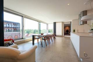 <p><span>Wonen op een uitzonderlijke locatie met panoramisch uitzicht: exclusief appartement in de iconische Silo's!</span></p><p><span>Het Project Kanaal van Axel Vervoordt is een unieke bestemming waar wonen, kunst, architectuur en gastronomie samenkomen. Omgeven door water, groen en indrukwekkende industriële erfgoedarchitectuur geniet u hier dagelijks van rust, ruimte en een inspirerende leefomgeving. Authentieke elementen, tijdloze architectuur en duurzame materialen vormen samen een unieke leefomgeving waar karakter, comfort en esthetiek perfect in balans zijn. Dankzij de strategische ligging in Wijnegem, vlak bij Schilde en Antwerpen, combineert deze unieke locatie het beste van twee werelden: een rustige, groene woonomgeving met alle voorzieningen en uitvalswegen in de onmiddellijke nabijheid.</span></p><p><span>Gelegen op de vierde verdieping van de Silo's geniet dit exclusieve appartement van ca. 202 m² van een panoramisch uitzicht over het Albertkanaal en het prachtig aangelegde domein. Het interieur werd ontworpen door binnenhuisarchitect Marc Lauwers en combineert tijdloze elegantie met uitzonderlijk wooncomfort.</span></p><p><span>De unieke indeling bestaat uit drie cirkelvormige ruimtes met elkaar verbonden door middel van kleine glazen bruggen en een transparant vierkant volume. Bij het binnenkomen treft u een sfeervolle bibliotheekruimte, een gastentoilet en een polyvalente kamer die dienst kan doen als logeer-, hobby- of bureauruimte.</span></p><p><span>Het hart van het appartement wordt gevormd door de indrukwekkende leefruimte met open keuken en eetgedeelte. Dankzij de grote glaspartijen aan drie zijden baadt deze ruimte de hele dag in natuurlijk licht en geniet u van een voortdurend contact met de omgeving. De hoogwaardige keuken werd sober en stijlvol vormgegeven met zeer kwalitatieve materialen en toestellen.</span></p><p><span>De tweede cirkelvormige ruimte herbergt een royale zithoek met centrale gashaard, waar de gebogen architectuur zorgt voor een warme en rustgevende sfeer.</span></p><p><span>De master suite beschikt over maatwerkkasten en een luxueuze badkamer uitgerust met een dubbel lavabomeubel, ligbad, inloopdouche en afzonderlijk toilet. De westelijke oriëntatie zorgt hier voor een aangename avondzon.</span></p><p><span>Een ondergrondse autostaanplaats is bijkomend aan te kopen voor +30.000€. Verder beschikt u over 2 eigen fietsenplaatsen en gebruiksrecht van de tuin.</span></p><p><span>Bijzonderheden: high-end afwerking, EPC-label A, ventilatiesysteem D, panoramische zichten en een unieke architecturale woonbeleving.</span></p><p><span>Maandelijkse gemeenschappelijke kosten: ca. 300€</span></p><p><span>Contacteer ons voor meer informatie of een bezoek!</span></p><p><span> </span></p><p><span> </span></p>