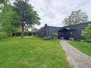 Deze ruime gezinswoning is gelegen op een uitzonderlijke, quasi verkeersvrije locatie in Drongen, verscholen in een rustige eenrichtingsstraat net buiten Gent. De absolute troef van deze bungalow is het unieke en blijvende uitzicht op de Vinderhoutse bossen. Hier woont u te midden van de natuur, op minder dan 10 kilometer van het Gentse stadscentrum.<br /><br />De woning opent groots met een indrukwekkende dubbele living van maar liefst 50 m², uitgerust met een sfeervolle open haard en cassette. De aansluitende open keuken beschikt over grote raampartijen die zorgen voor een overvloed aan natuurlijk daglicht en een naadloze overgang naar de tuin. De bungalow kent een praktische, gelijkvloerse indeling met vier volwaardige slaapkamers, een aparte bureauruimte en een extra hobbyruimte.<br /><br />Ook op het vlak van comfort blinkt de woning uit. In 2025 werd de badkamer vernieuwd met een moderne inloopdouche en werd er een nieuw, apart toilet geïnstalleerd. Als ultieme luxe beschikt de woning over een eigen sauna om volledig in te ontspannen. De zone rondom de bungalow is volledig aangelegd als een rustige privétuin die perfect aansluit op de bosrijke omgeving.<br /><br />Indeling van de woning:<br />inkomhal - dubbele leefruimte - open keuken - bureau - nachthal - apart toilet - slaapkamer 1 - slaapkamer 2 - slaapkamer 3 - slaapkamer 4 - badkamer met inloopdouche - sauna - hobbyruimte - tuin.<br /><br />Beschikbaar vanaf: 01/09/2026
