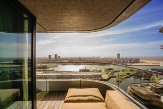 <strong>Uniek wonen op de 21ste verdieping aan de Oosteroever</strong><br /><br />Op zoek naar een <strong>exclusief appartement te koop in Oostende met zeezicht</strong>?<br />Dit prachtig afgewerkte appartement op de <strong>21ste verdieping in de begeerde wijk Oosteroever</strong> biedt een uitzonderlijke woonbeleving met sublieme vergezichten over de <strong>zee, duinen, haven en de skyline van Oostende</strong>.<br /><br />Dit hedendaagse appartement, gebouwd in <strong>2021</strong>, combineert een hoogwaardige afwerking met hedendaags comfort en een indrukwekkende ligging. Dankzij de grote hoogte geniet u vanuit de leefruimtes en de masterbedroom van een uniek en voortdurend veranderend panorama.<br /><br /><strong>Ruime woonkamer met terras en adembenemend uitzicht</strong><br />Via de inkomhal komt u in de stijlvolle en aangename leefruimte.<br />De <strong>ruime woonkamer met sierhaard</strong> vormt het hart van het appartement en geniet dankzij de ligging op de 21ste verdieping van bijzonder veel licht en prachtige vergezichten.<br />Aansluitend bevindt zich het <strong>aangename terras</strong>, de ideale plek om te genieten van een ochtendkoffie, een aperitief bij zonsondergang of simpelweg van het weidse uitzicht over <strong>zee, duinen, haven en stad</strong>.<br />De volledige leefruimte is afgewerkt met <strong>parket</strong>, wat zorgt voor een warme en elegante uitstraling.<br /><br /><strong>Hedendaagse open keuken, volledig ingericht</strong><br />De moderne, open keuken sluit naadloos aan bij de woonkamer en vormt een stijlvol en functioneel geheel.<br />De keuken is <strong>volledig ingericht</strong> en biedt alles wat nodig is voor comfortabel dagelijks wonen en gezellig tafelen.<br />De open indeling versterkt het gevoel van ruimte en zorgt voor een aangename verbinding tussen keuken, eet- en leefruimte.<br /><br /><strong>Drie slaapkamers, waaronder een masterbedroom met subliem zeezicht</strong><br />Het appartement beschikt over <strong>3 volwaardige slaapkamers</strong>.<br />De <strong>masterbedroom</strong> is een echte troef en biedt eveneens een prachtig <strong>zicht op zee</strong>. Deze slaapkamer beschikt bovendien over een <strong>eigen badkamer met ligbad, dubbele lavabo en toilet</strong>, wat zorgt voor extra privacy en comfort.<br />De twee overige slaapkamers zijn ideaal als logeerkamers, kinderkamers, dressing of thuiskantoor. Zij delen een tweede badkamer, uitgerust met een <strong>douche en lavabo</strong>.<br />Daarnaast beschikt het appartement over een <strong>afzonderlijk gastentoilet</strong> en een praktische <strong>bergruimte</strong>.<br /><br /><strong>Hoogwaardige afwerking en hedendaags wooncomfort</strong><br />Het appartement werd gebouwd in <strong>2021</strong> en is bijzonder mooi afgewerkt. De aanwezigheid van <strong>parket doorheen het appartement</strong> zorgt voor een luxueuze en uniforme uitstraling.<br />Voor het verwarmingscomfort is er <strong>vloerverwarming</strong>, aangesloten op het <strong>warmtenet</strong>. Met een <strong>EPC-label A</strong> combineert deze woning hedendaags comfort bovendien met een uitstekende energieprestatie.<br /><br /><strong>Garage mogelijk in de directe omgeving</strong><br />Er bestaat de <strong>mogelijkheid tot aankoop van een garage in de directe omgeving</strong> van het appartement. Een interessante extra troef voor wie comfortabel en veilig wil parkeren in Oosteroever.<br /><br /><strong>Exclusief appartement te koop in Oostende Oosteroever</strong><br />Dit ruime en luxueus afgewerkte <strong>3-slaapkamerappartement in Oostende – Oosteroever</strong> is een unieke kans voor wie op zoek is naar een hoogwaardige woonst op grote hoogte, met <strong>panoramisch zeezicht en zicht over de haven, duinen en stad</strong>.<br /><br />De combinatie van de <strong>21ste verdieping, het uitzonderlijke uitzicht, het ruime terras, 3 slaapkamers, 2 badkamers, open keuken, parketafwerking, vloerverwarming, warmtenet en EPC A</strong> maakt dit appartement bijzonder aantrekkelijk als permanente woning, tweede verblijf of kwalitatieve investering aan de Belgische kust.<br /><br /><strong>Kenmerken in het kort</strong><br /><span>Aangenaam terras met prachtig uitzicht</span><br /><span>Prachtige parketafwerking doorheen het appartement</span><br /><span>Bouwjaar 2021</span><br /><span>EPC : label A</span><br /><span>Vloerverwarming - aangesloten op het warmtenet</span><br /><span>KI: € 1.102</span><br /><span>Mogelijkheid tot aankoop van garage in de directe omgeving</span><br /><br /><strong>Een exclusieve woonbeleving op hoogte, met de zee als dagelijkse achtergrond.</strong><br />
