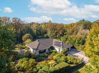 <strong>Prachtige en instapklare gelijkvloersvilla met unieke parktuin op 2.086 m² (ZW)</strong><br /><br /><strong>Zeer gunstig en rustig gelegen</strong> in villawijk <strong>"De Lint" </strong>te Oud-Turnhout, met een vlotte bereikbaarheid naar winkels, scholen, openbaar vervoer en de autostrade E34 Antwerpen-Eindhoven.<br /><br />Deze <strong>aangename en ruime gelijkvloerswoning</strong> bestaat uit een inkomhal, gastentoilet, een ruime en lichtrijke leefruimte op visgraatparket die volledig werd ingericht rond de gezellige open gashaard en een volledig ingerichte keukenhoek. De keuken werd voorzien van een kookvuur, dampkap, nieuwe vaatwasser, grote koelkast, combi-oven, heel wat kastruimte en een mooi granieten werkblad. De leefruimte werd volledig omgeven door groen en brengt zo de nodige rust na een drukke werkdag!<br /><br />Verder treffen we op het gelijkvloers <strong>twee ruime slaapkamers met ensuite badkamers </strong>die recent vernieuwd werden en waarvan 1 werd ingericht met eigen infraroodsauna en een bureauruimte of extra 3e slaapkamer. Via de ruime inpandige garage voor 2 wagens komen we terecht in de bovenverdieping waar eveneens nog een extra grote slaapkamer met eigen badkamer werd ingericht.<br />Op deze verdieping nog heel wat opbergruimte die men eventueel nog kan omvormen naar extra kamers.<br /><br />De nodige zaken werden ondernomen om de woning energiezuinig en future proof te maken door het plaatsen van <strong>18</strong> <strong>zonnepanelen met thuisbatterij</strong>, extra isolatie enz. <br /><br /><strong>Uniek </strong>aan deze woning is dat zij gelegen is in een echte <strong>parktuin van 2.086 m²</strong>, een oase van rust en volgroeid en onderhoudsvriendelijk groen met een mooie vijverpartij, gezellige terrassen en aangename rusthoekjes. De tuin werd geörienteerd naar het zuidwesten. Hier is het elke dag vakantie! <br /><br />De woning werd volledig omheind, biedt <strong>absolute privacy </strong>en is voorzien van een extra carport en tuinhuisjes. <br />Hier kan je genieten van je eigen paradijsje!<br /><br /><strong>Bijzonderheden:</strong><br />-gunstige ligging<br />-unieke parktuin<br />-3 badkamers<br />-18 zonnepanelen en thuisbatterij<br />-instapklaar<br />-asbestveilig<br />-goedgekeurde elektriciteit