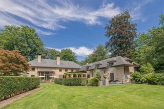 <p><span>Dit royale landhuis is gelegen op een ruim perceel van ruim 1 Ha met alle rust en privacy. De aangelegde parktuin biedt u een tennisterrein, ruime terrassen, verwarmd buitenzwembad etc. </span></p><p><span>Een uniek eigendom met vele mogelijkheden!</span></p><p><span> </span></p><p><span>Indeling</span></p><p><span>U betreedt de villa middels de dubbele voordeur naar een prachtige inkomhal met vide, gastentoilet met handenwasser en vestiaireruimte. Toegang naar de leefruimte alsook een doorgang naar de eetkamer. De ruime eetkamer heeft een ronde raampartij aan de voorzijde van de villa. Mede dankzij deze vorm is de eetkamer een zeer sfeervolle ruimte waar u een prachtig diner kunt organiseren. Via de tweede gang bereikt u vanuit de eetkamer ondermeer de leefkeuken , bar alsook de familyroom en zij-inkom. </span></p><p><span>De living bestaat uit een ruime woonkamer met gigantische open haard en vide naar de nachthal. Dankzij deze indrukwekkende plafondhoogte beschikt deze leefruimte ook over zeer hoge raampartijen met prachtig lichtinval en schitterend zicht op de tuin. Een tweede gedeelte van de living is de televisiekamer met eveneens een open haard. Aansluitend toegang tot een mooi ingericht kantoor. </span></p><p><span>De royale leefkeuken is mogelijk de belangrijkste ruimte van deze villa. Centraal gelegen in de woning en bereikbaar zowel vanuit de living alsook via de gang naar de eetkamer. Deze royale leefkeuken met open haard werd ingericht met een prachtige maatwerk keuken in eik en is voorzien van alle toestellen waaronder een prachtig fornuis. Vanuit de keuken ook toegang tot de tuin en het aangrenzende overdekte terras.</span></p><p><span>Voorts nog een tweede kantoor of familyroom met aparte inkom, een bar of aperitiefruimte, zij-inkom met mudroom alsook een aparte wellness met kleedruimtes, sanitaire voorzieningen en een sauna, dit alles grenzend aan het terras bij het zwembad. </span></p><p><span> </span></p><p><span>Eerste verdieping</span></p><p><span>Bereikbaar middels twee trappen alsook een lift heeft deze villa een zeer ruime eerste verdieping met drie gedeeltes; twee kinder-afdelingen met steeds twee slaapkamers welke een badkamer delen, een polyvalente kamer ( vijfde slaapkamer of hobbyruimte) en een zeer royale mastersuite bestaande uit een ruime slaapkamer, volledig ingerichte dressingkamer en een luxe afgewerkte badkamer. De separate waskamer is ingericht met kasten en aansluitingen voor de toestellen.</span></p><p><span> </span></p><p><span>Tweede verdieping</span></p><p><span>Middels de lift bereikt u de polyvalente zolder. Deze zeer grote ruimte biedt u alle mogelijkheden voor het realiseren van bijkomende slaapkamers, kantoor aan huis, fitness, alle mogelijkheden dus!</span></p><p><span> </span></p><p><span>Kelder</span></p><p><span>Vanuit de keuken bereikt u de kelder alwaar u eerst de wijnkelder met degustatieruimte betreedt om vervolgens nog verschillende bergruimtes en technische ruimtes te kunnen bereiken.</span></p><p><span> </span></p><p><span>Garages</span></p><p><span>De villa beschikt momenteel niet over een garage, echter is er de mogelijkheid tot bouwen van een vrijstaand garagegebouw of carport. Tevens is er een nog een oude conciërgewoonst welke kan worden veranderd naar – of vervangen door een garagegebouw. </span></p><p><span> </span></p><p><span>Tuin en buitenruimtes</span></p><p><span>De aangelegde parktuin is volledig omheind en voorzien van een aparte inrijpoort en uitgang. De tuin is voorzien van tuinverlichting alsook een beregeningsinstallatie. Tennisterrein op gravelbodem, ruim verwarmd zwembad met automatisch roldek, bijgebouw of tuinberging. </span></p><p><span> </span></p><p><span>Bijzonderheden</span></p><p><span>Deze zeer ruime villa werd gebouwd met gebruik van hoogwaardige materialen en voorzien van moderne luxe en comfort. De woning beschikt over een uitgebreid alarmsysteem, domotica, etc. </span></p><p><span> </span></p><p><span>Meer inlichtingen via ons kantoor</span></p>
