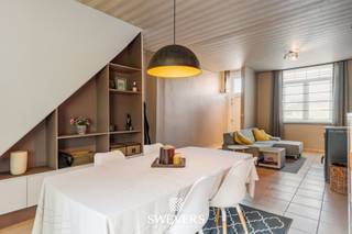 Voor meer info en foto’s, surf naar www.swevers.be – verzorgde en gerenoveerde rijwoning met centrale ligging aan de Lommelsesteenweg 50 in Leopoldsburg. De woning werd oorspronkelijk gebouwd in 1936, grondig gerenoveerd in 2010 en voorzien van nieuwe beglazing in 2018. Met een bewoonbare oppervlakte van ongeveer 130 m² biedt deze woning een praktische indeling en verrassend veel ruimte. Via de inkomhal bereikt u de ruime leefruimte van ca. 34 m² met plaats voor een gezellige zithoek en eetkamer. Aansluitend bevindt zich de keuken van 13,7 m² met rechtstreekse toegang tot de tuin. Verder zijn er op het gelijkvloers een badkamer en een praktische berging. Op de eerste verdieping bevinden zich twee volwaardige slaapkamers van ca. 16,4 m² en 12,9 m². De ruime zolder van ongeveer 30 m², bereikbaar via een vaste trap, kan mits afwerking ingericht worden als derde slaapkamer, hobbyruimte, bureau of extra leefruimte. Het perceel van 2 are 24 centiare beschikt over een oostgerichte tuin waar u in alle rust van het buitenleven geniet. Ook technisch zit het goed: het dak werd vernieuwd tijdens de renovatie, alle ramen werden vervangen in 2018 en de elektriciteit is conform. Dankzij de centrale ligging bevinden scholen zich op ca. 600 meter en winkels, horeca en openbaar vervoer op ongeveer 1 kilometer. Ook de snelweg ligt vlot bereikbaar op ca. 11 kilometer. Een ideale woning voor starters, gezinnen of wie op zoek is naar een instapklare woning met uitbreidingsmogelijkheden. Voor meer informatie, bel 011 255 155. Bron bewoonbare oppervlakte: EPC – verslag. Dit pand is onderworpen aan de renovatieverplichting van de Vlaamse overheid voor residentiële gebouwen (behoudens bij sloop binnen 5 jaar na de aankoop). Consulteer voor meer informatie de website van het Vlaams Energie- en Klimaatagentschap via https://www.vlaanderen.be/een-huis-of-appartement-kopen/renovatieverplichting-voor-residentiele-gebouwen.