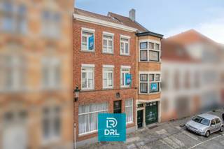 Op een <strong>absolute topligging in het historische centrum van Brugge</strong>, vlak bij het Simon Stevinplein en op wandelafstand van de Markt, bieden wij een bijzonder vastgoedensemble aan met een zelden geziene combinatie van <strong>ruimte, karakter, comfort en mogelijkheden</strong>.<br />Het geheel bestaat uit <strong>vier onroerende goederen</strong>: <strong>Zilverstraat 17</strong>, <strong>Zilverstraat 19</strong>, het woongedeelte van <strong>Steenstraat 56</strong> <em>(exclusief het handelsgelijkvloers)</em> en een <strong>overdekte staanplaats voor twee wagens in de Kopstraat</strong>.<br />De verschillende eigendommen vormen samen een uitzonderlijk geheel en bieden tal van mogelijkheden voor <strong>wonen en werken onder één dak, vrije beroepen, kantoor of praktijk, atelier, een ruime stadsresidentie of een combinatie hiervan</strong>.<br />Een absolute blikvanger is bovendien het <strong>fantastische uitzicht over de historische binnenstad, het Simon Stevinplein en de drie iconische Brugse torens</strong>.<br /><br /><u>Zilverstraat 17</u><br />Achter de brede, karaktervolle gevel gaat een verrassend ruim pand schuil.<br />Op het gelijkvloers bevinden zich een <strong>bureau-/praktijkruimte</strong>, toilet en een bijzondere multifunctionele ruimte waarin zich een <strong>binnenzwembad</strong> bevindt. Het zwembad is momenteel volledig afgedekt met een houten vloer, waardoor deze ruimte vandaag perfect als hobby- of ontspanningsruimte kan worden gebruikt. De oorspronkelijke zwembadfunctie kan opnieuw zichtbaar worden gemaakt.<br />Via de traphal bereikt men de bovenliggende woonvertrekken met onder meer een <strong>leefruimte, keuken en terras</strong>, gevolgd door een nachthal, slaapkamer en badkamer.<br /><br /><u>Zilverstraat 19</u><br />Het naastgelegen pand is onmiddellijk herkenbaar aan zijn karakteristieke <strong>vooruitstekende gevel</strong> en vormt mee de verbinding tussen de verschillende delen van het vastgoedensemble.<br />Het omvat onder meer een <strong>inkomhal, inpandige garage, kelder, toilet, twee bergingen, keuken en achterplaats</strong>.<br />Vanuit dit gedeelte is er via <strong>trap én lift</strong> verbinding met de bovenliggende verdiepingen en met Steenstraat 56.<br />De verdiepingen omvatten onder meer een <strong>bureau-/atelierruimte met toilet</strong>, meerdere kamers, verschillende badkamers, toiletten en een terrasje. Ook de zolderverdieping werd ingericht met bijkomende kamers en sanitair.<br /><br /><u>Steenstraat 56</u><br />Aan de zijde van de Steenstraat bevindt zich een bijzonder karaktervol historisch pand met een prachtige trapgevel.<br /><strong>Het handelsgelijkvloers behoort niet tot het aangeboden vastgoed.</strong><br />Het woongedeelte omvat onder meer een <strong>leefruimte, salon/zitplaats, keuken, veranda, bureau, berging en toilet</strong>. Op de verdieping bevinden zich <strong>twee slaapkamers, een badkamer en terras</strong>, aangevuld met een zolderruimte.<br />Vanuit de hoger gelegen ruimtes geniet men van prachtige vergezichten over de Brugse binnenstad en zijn monumentale skyline.<br /><br />Ondanks het uitgesproken historische karakter beschikt het geheel over verschillende hedendaagse comfortelementen. Zo zijn er <strong>diverse airconditioningstoestellen</strong> aanwezig en zorgt de <strong>lift</strong> voor extra comfort en een praktische verbinding tussen verschillende niveaus van het complex. De combinatie met het binnenzwembad, terrassen en buitenruimtes maakt het geheel des te uitzonderlijker.<br /><br />Een niet te onderschatten troef in het centrum van Brugge is de aanwezigheid van een <strong>overdekte staanplaats voor twee wagens in de Kopstraat</strong>. Samen met de garage in Zilverstraat 19 betekent dit een bijzonder waardevolle parkeerfaciliteit op een locatie waar private parkeermogelijkheden uiterst schaars zijn.<br /><br />Dit is geen klassieke stadswoning, maar een <strong>uniek en veelzijdig vastgoedensemble</strong> met verschillende adressen en toegangen, royale volumes, garage, lift, zwembad, terrassen, werk- en praktijkruimtes en parkeerplaats voor twee wagens.<br /><br />Meer info of een bezoek inplannen, bel of mail DRL VASTGOED, 050 65 95 95 of info@drlvastgoed.be<br />