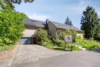 Ontdek deze prachtige villa in Dilbeek, omringd door het groen. Hier woont u in alle privacy, aan een doodlopend wegje, en toch op korte afstand van de invalswegen. <br /><br />De woning is gebouwd midden in een royale tuin van 1.521 m². De tuin en het ruime terras genieten de hele dag van zonlicht. Aangrenzend ligt een apart tuinperceel van 1.704 m². Dit is momenteel een fruitboomgaard, maar kan ook perfect talrijke andere doeleinden. De solide constructie en de praktische indeling maken deze woning bijzonder aantrekkelijk. U wordt verwelkomd in een lichtrijke inkomhal met een centrale leefruimte die, samen met de open keuken, de centrale inbouwhaard en de grote raampartijen, het hart van het huis vormt. Op de tussenverdieping bevinden zich drie ruime slaapkamers en een volledig uitgeruste badkamer. De eerste verdieping bevat een ruime slaapkamer en een tweede badkamer. De royale zolder is volledig vernieuwd en geïsoleerd en kan ingericht worden tot bijkomende kamers, speel- of bergruimte. <br />De woning is recent met veel smaak gerenoveerd en is volledig instapklaar. Er werd gebruik gemaakt van hoogwaardige materialen, waaronder vloerverwarming en zonnepanelen. Dankzij het gunstige EPC-label B geldt er geen renovatieverplichting. De woning beschikt over een regenwaterput (3000l) alsook over een grondwaterput en leidingwater. <br />Extra troeven: <br />- Inpandige garage en een ruime oprit met plaats voor meerdere wagens. <br />• Ruime kelder van ca. 50 m² (stockage, hobbyruimte of wijnkelder) <br />• Mogelijkheid tot praktijkruimte te maken van 123 m² – ideaal voor een vrij beroep of zelfstandige activiteit aan huis <br />• Een solide stal, die tevens plaats biedt voor een hobbyproject <br />Een woning met uitzonderlijke troeven: privacy, perceelgrootte, solide constructie en tal van mogelijkheden voor wonen en werken in een groene omgeving. Voor extra informatie en een bezoek: www.bosweg6.be