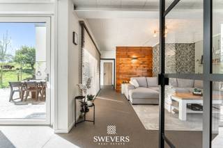 Voor meer info en foto’s, surf naar www.swevers.be –<br /><br />In het charmante gehucht Lauw, deelgemeente van Tongeren, vind je deze statige open bebouwing uit 1947 te Donkelstraat 52 op een perceel van 8are45ca. De woning werd in 2022 grondig gerenoveerd met behoud van karaktervolle elementen en biedt modern wooncomfort in een groene omgeving. Met een bewoonbare oppervlakte van 235 m² is dit de ideale gezinswoning, perfect ook voor thuiswerkers of hobbyisten.<br /><br />De lichtrijke leefruimte van 29,8 m² geeft via grote raampartijen uitzicht op de achterliggende weilanden. De keuken van 26,9 m² is strak ingericht en voorzien van een kookeiland, hoogwaardige toestellen en directe toegang tot het zuidgerichte terras—perfect voor zomerse avonden.<br /><br />Er zijn vier volwaardige slaapkamers (15, 14,4, 12,3 en 12,2 m²), waarvan de master bedroom is uitgerust met een riante inloopdressing van 12,2 m². Twee luxueuze badkamers (16 en 14,32 m²) bieden alle comfort, inclusief bad, inloopdouche en dubbele wastafels. Een extra gastentoilet is eveneens aanwezig.<br /><br />Praktisch scoort de woning sterk dankzij de ruime kelder met meerdere bergingen en een perceel van 8a45 met voldoende parkeergelegenheid. Een vergunning voor een carport is reeds verkregen. Duurzaamheid komt aan bod via een regenwaterput van 10.000 liter.<br /><br />De witgrijs gekaleide gevel en het tijdloze interieur met warme materialen creëren een hedendaagse, sfeervolle woonstijl. Dankzij de zuidgerichte oriëntatie geniet je hier van maximale lichtinval en zonovergoten buitenmomenten.<br /><br />Voor meer informatie, bel 012 699 900. Bron bewoonbare oppervlakte: EPC – verslag.