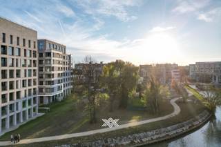 Dit ruime en kwalitatief afgewerkte appartement van 99 m² met een terras van 15 m² maakt deel uit van het recente nieuwbouwproject Liv De Molens. Het appartement omvat twee slaapkamers en een lichtrijke leefruimte met open keuken. De grote raampartijen zorgen voor een overvloed aan natuurlijk licht en bieden een rechtstreeks zicht op de Leie. Het westelijk georiënteerd terras heeft een oppervlakte van 15 m². De afwerking is van hoog niveau, met onder meer vloerverwarming, parketvloeren en duurzame materialen die bijdragen aan een aangenaam en energie-efficiënt wooncomfort. Dankzij de doordachte indeling is dit appartement geschikt voor zowel eigen bewoning als investering. Naast de ondergrondse berging die is inbegrepen in de prijs, kan er ook een ondergrondse staanplaats worden aangekocht aan de prijs van 35.000 euro. Het appartement is momenteel verhuurd aan €950 per maand, exclusief €80 provisie, wat het tot een interessante investeringsopportuniteit maakt met onmiddellijk rendement. Indien de koper het pand zelf wenst te betrekken, dient rekening te worden gehouden met de wettelijke opzegtermijnen. De verkoop vindt plaats onder het tarief van 2% registratierechten bij aankoop als enige en eigen woning, of 12% voor investeringsdoeleinden. Epeil 22 / centrale verwarming op aardgas 