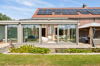 Verscholen tussen uitgestrekte weilanden en weidse vergezichten bevindt zich deze uitzonderlijke langgevelhoeve op een privédomein van 6.920 m². Een zeldzame eigendom waar de sereniteit van het platteland hand in hand gaat met een uitstekende bereikbaarheid. Dankzij de nabijheid van de E19 en A12 bereikt u Antwerpen, Brussel en Mechelen in alle comfort.<br /><br />Met respect voor haar rijke geschiedenis werd deze karaktervolle hoeve volledig gerenoveerd volgens de hoogste standaarden. Authentieke elementen werden zorgvuldig bewaard en gecombineerd met hedendaags wooncomfort, hoogwaardige materialen en moderne technieken. Het resultaat is een tijdloze woning waar karakter en verfijning elkaar moeiteloos versterken.<br /><br />De woning biedt een bewoonbare oppervlakte van 337 m² en is vandaag ingericht met twee royale slaapkamers, dressing en twee afgewerkte badkamers. Wie extra ruimte wenst, kan de woning eenvoudig uitbreiden naar drie of vier slaapkamers, zonder afbreuk te doen aan het doordachte ontwerp.<br /><br />Ook op technisch vlak voldoet dit eigendom volledig aan de hedendaagse verwachtingen, met een EPC-label B, 45 zonnepanelen, een conforme AREI-keuring en een asbestveilig attest. De villa werd ontworpen als een exclusieve privéretraite waar ontspanning centraal staat. Een verwarmd zwembad met elegant bankirai terras vormt samen met de vijver, het charmante badhuis en de exclusieve Michael Phelps Signature Swim Spa een uitzonderlijke wellnessomgeving die uitnodigt om het hele jaar door te genieten. De aangebouwde veranda, afgewerkt met een natuurstenen vloer, vloerverwaming en zonneschermen, baadt in natuurlijk licht en biedt een panoramisch uitzicht over het omliggende landschap. Tot slot is er ook een wijnkelder.<br /><br />Als vastgesteld bouwkundig erfgoed, gelegen in landschappelijk waardevol agrarisch gebied, bezit deze langgevelhoeve een uitzonderlijke zeldzaamheid. Een eigendom voor wie geen compromis wil sluiten tussen authenticiteit, privacy, ruimte en hedendaagse luxe. Een plaats waar geschiedenis zorgvuldig werd bewaard en een exclusieve levensstijl vanzelfsprekend aanvoelt.