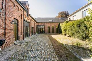 Deze uitzonderlijk ruime woning in het centrum van Haaltert biedt enorm veel plaats en tal van mogelijkheden. Dankzij de verschillende leefruimtes is de eigendom perfect geschikt voor een groot gezin, een kangoeroewoning of een combinatie van wonen en werken. Op het gelijkvloers vind je meerdere gezellige leefruimtes, twee slaapkamers en een functionele keuken met gasfornuis. Aansluitend is er een praktische berging met een authentieke houtoven. Een van de slaapkamers beneden beschikt over een vaste trap naar de ingerichte zolder, die voorzien is van een eigen douche en toilet. Op de verdieping bevindt zich een bijzonder ruime leefruimte, een extra living, een badkamer met ligbad en een grote zolderkamer die ideaal kan dienen als bijkomende slaapkamer, hobbyruimte of atelier. Ook buiten heeft deze eigendom heel wat te bieden. Je ontspant op het overdekte terras of het tweede terras, met daartussen een mooie vijver die zorgt voor een rustige sfeer. Vooraan ligt een ruime binnenkoer, terwijl je achteraan beschikt over een grote, groene tuin met verschillende fruitbomen en heel wat privacy.