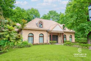 <p><strong>Riante energiezuinige villa met binnenzwembad en maximale privacy</strong></p>
<p>Op zoek naar luxe, ruimte en rust? Deze exclusieve villa, gelegen op een residentieel en rustig perceel van 2.477 m², biedt het allemaal. Met een bewoonbare oppervlakte van maar liefst 540 m² geniet je hier van comfortabel en energiezuinig wonen in een groene, discrete omgeving.</p>
<p>De woning werd gebouwd in 2006 en is voorzien van alle hedendaagse comfort. De ruime woonkamer met open leefkeuken baadt in natuurlijk licht en vormt het hart van het huis. De gehele gelijkvloerse verdieping is voorzien van gepantserd glas. Verder beschikt de villa over 5 volwaardige slaapkamers en 4 badkamers – ideaal voor grotere gezinnen of wie graag gasten ontvangt.</p>
<p>Voor ontspanning hoef je de deur niet uit: het luxe binnenzwembad zorgt voor een permanent vakantiegevoel. Ook thuiswerken wordt een plezier dankzij de grote kantoorruimte. Bovendien is er een aparte studio, perfect als gastenverblijf, praktijkruimte of voor inwonende hulp.</p>
<p>Buiten geniet je van een overdekt terras en een prachtig aangelegde tuin die volledige privacy garandeert. De dubbele garage maakt het plaatje compleet.</p>
<p>Bij het betreden van deze riante en energiezuinige villa komt u via de inkomhal meteen in de ruime leefruimte terecht. De woonkamer met gezellige zithoek en gashaard vloeit naadloos over in de eetplaats en de open leefkeuken, die voorzien is van alle hedendaags comfort – een ideale plek voor wie graag kookt en gasten ontvangt.</p>
<p>Een stijlvolle glazen wand scheidt de woonkamer van het binnenzwembad. Hoewel het zwembad momenteel buiten gebruik is, zijn alle technieken aanwezig om dit eenvoudig opnieuw in werking te stellen. Momenteel wordt de ruimte gebruikt als fitnessruimte, maar ze biedt ook andere mogelijkheden zoals wellness of hobbyruimte. Aansluitend bevinden zich een technische ruimte en een welnessgedeelte met sauna, douche en toilet. Een trap leidt hier naar een grote polyvalente ruimte op de verdieping, uitgerust met airconditioning en momenteel ingericht als kantoor.</p>
<p>Op het gelijkvloers is ook een ruime dubbele garage met toegang tot de kelder. Tussen de keuken en garage bevindt zich een tweede trap die leidt naar een studio, bestaande uit twee slaapkamers en een badkamer met douche, lavabo en toilet – ideaal als gastenverblijf of voor inwonende hulp.<br /><br />Vanuit de centrale inkomhal vertrekt een derde trap naar de bovenverdieping, waar u de masterbedroom vindt, uitgerust met parketvloer, airconditioning en gashaard. De master beschikt over een aanpalende dressing en een eigen badkamer met bad, douche en toilet. Daarnaast zijn er nog twee extra slaapkamers met parket en een aparte badkamer met ligbad, lavabo en toilet. Een gastentoilet is eveneens voorzien op het gelijkvloers.</p>
<p><strong>Buitenleven in alle comfort</strong></p>
<p>Grenzend aan de woonkamer bevindt zich een ruim overdekt terras, uitgerust met elektrische rolschermen en terrasverwarming – ideaal om het hele jaar door van buiten te genieten. Een tweede terras ligt aan het binnenzwembad. De aangelegde tuin rondom de woning biedt volledige privacy en rust. Verder beschikt het domein over een carport en een professioneel alarmsysteem.</p>
<p>Een unieke combinatie van ruimte, luxe en rust. Klaar om jouw nieuwe thuis te worden?</p>