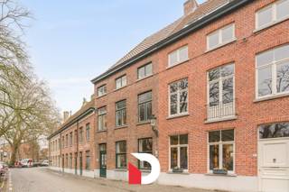 Deze statige burgerwoning is gelegen op een van de meest exclusieve en idyllische pleinen van het historische Brugse stadscentrum, namelijk het Wijngaardplein in het Minnewater. Het eigendom beschikt over een uiterst rationele en praktische indeling.<br />Via een lange inkomhal met hoge plafonds komen we de woonst binnen, verder een 2 ledige leefruimte met zithoek en eetplaats. Deze ruimte is voorzien van een gezellige plankenvloer en 2 authentieke open haarden. <br />Achteraan de woning (met zicht op de koer) vinden we de reeds vernieuwde keuken terug met kookeiland en naastgelegen praktische bijkeuken/berging, een naastgelegen wasplaats en apart gastentoilet.<br /><br />Vanuit de keuken hebben we zicht op de gezellige buitenkoer die uitzicht heeft over het achtergelegen Brugs reitje. <br /><br />Op de eerste verdieping vinden we 2 riante slaapkamers, een grote badkamer en apart toilet op de hall terug. <br />De tweede verdieping is identiek, dus ook 2 riante slaapkamers, badkamer en apart toilet. In totaal zijn er dus 4 grote slaapkamers en 2 badkamers aanwezig. <br /><br />Verder heeft deze woning nog een ruime zolderverdieping en kelderverdieping die nu enkel dienst heeft als bergruimte. <br /><br />Contacteer ons snel voor een bezoek aan dit unieke eigendom via info@delbecque.immo of 050 45 03 45
