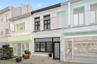 <p><span><span>Midden in het hart van de stad, ligt deze pas vernieuwde woning met wit geschilderde voorgevel en hoge plafonds. Zowel de technieken (elektriciteit en verwarming) als de afwerking zijn nieuw: zwarte alu-ramen met hoogrendementsglas, ingebouwde led-plafondspots, condensatieketel (gas), ventilatieroosters, videofoon, vernieuwd zadeldak en bakgoot, etc. Op het gelijkvloers vangt de living veel licht door grote raampartijen tot plafondhoogte. De keramische tegels met houtmotief zijn geschrankt gelegd. Een achterdeur maakt de kleine koer toegankelijk vanuit de leefruimte. De grote toiletruimte (hangtoilet), werd verfraaid met een lavabomeubel. De keuken bevindt zich op een tussenniveau, dat bereikbaar is via een stevige betontrap met bekleding. Deze ingerichte greeploze eetkeuken met hoogglans, beschrijft een L-vorm en omvat volgende apparaten: koelkast, diepvriezer, oven, kookplaat, dampkap en een vaatwasser. De badkamer boven beschikt over een zwart meubel met ronde spiegel (ingebouwde verlichting), hangtoilet, inloopdouche (regenfunctie) met glazen wand en een witte designradiator. Aan de straatzijde op de eerste verdieping ligt de master bedroom met laminaatvloer en twee hoge ramen. Onder dak neemt de open slaapkamer de hele verdieping in. Het plafond is afgewerkt tot in de nok. De haast perfecte officiële Mobiscore beloopt 9,6 op 10.</span></span></p>