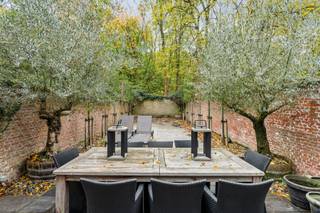 Aan de statige Jan Van Rijswijcklaan in Antwerpen prijkt dit sublieme herenhuis in Neo-Lodewijk XVI-stijl, een architecturaal juweel ontworpen door Edward Van Not in 1912, een naam die synoniem staat voor verfijning, symmetrie en onmiskenbare grandeur.<br /><br />Achter de sierlijke, evenwichtige gevel ontvouwt zich een woning waar ambacht, elegantie en comfort samensmelten tot een zeldzaam harmonisch geheel. Elk detail, van de hoge plafonds met lijstwerk tot de authentieke parketvloeren en marmeren open haarden, ademt karakter en verfijning.<br /><br />De leefruimtes baden in licht dankzij de hoge ramen en creëren een sfeer van stille luxe: groots, maar nooit overdreven. De indrukwekkende leefkeuken vormt het kloppend hart van de woning, een plek waar gastronomie en gezelligheid elkaar ontmoeten. De afwerking is ronduit uitzonderlijk: een Lacanche gasfornuis met teppanyaki-plaat, oven, magnetron, afzuigkap, koelkast met vriesvak en ingebouwde koffiemachine, allemaal samengebracht op een natuurstenen vloer die klasse uitstraalt.<br /><br />Vanuit de keuken kijkt u uit op een onderhoudsvriendelijke stadstuin, met een uniek en open zicht op het groene Hertogenpark, een zeldzaam privilege in het hart van de stad. Hier heerst een rust die contrasteert met de levendigheid van Antwerpen, slechts enkele minuten verderop.<br /><br />Op de tussenverdieping bevindt zich een intieme tv-ruimte met bar en toegang tot een groot betegeld terras van ca. 45 m², ideaal voor avonden in goed gezelschap, met een glas wijn en de stad zachtjes op de achtergrond.<br /><br />De slaapverdiepingen bieden ruimte en sereniteit: twee master suites met eigen dressing en luxueuze marmeren badkamers, aangevuld met vier extra slaapkamers, waarvan twee eveneens voorzien zijn van een eigen badkamer. Overal voelt men de doordachte indeling en het vakmanschap van een tijd waarin huizen nog met trots werden gebouwd.<br /><br />De woning is volledig onderkelderd en herbergt onder meer een wijnkelder, een subtiele knipoog naar levensgenieters die weten te waarderen wat echt goed is.<br /><br />Bijzonderheden<br />+ Terrassen en ramen achtergevel vernieuwd in 2023<br />+ Overal warmtepompen Lucht-Lucht<br />+ Alarmsysteem rechtstreeks verbonden met de politie<br />+ Luxueuze renovatie met topmaterialen<br />+ Volledig onderkelderd met wijnkelder<br />+ Mogelijkheid tot huren van autostaanplaats en garagebox<br /> 