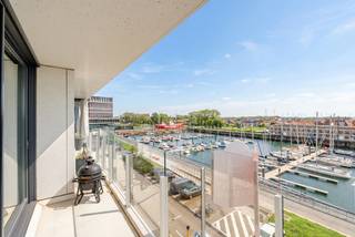 Op zoek naar een appartement met dat tikkeltje meer? Dit prachtig en bijzonder goed onderhouden appartement in een zeer recente residentie biedt een uitzonderlijke woonbeleving dankzij de fantastische ligging, hoogwaardige afwerking, optimale zuidoriëntatie en het adembenemende panoramische zicht over de jachthaven van Zeebrugge.

Bij het binnenkomen wordt u verwelkomd in een verzorgde inkomhal die toegang biedt tot de ruime en lichtrijke leefruimte. De open keuken, stijlvol geïntegreerd in het geheel, is voorzien van alle comfort en beschikt over een indrukwekkend groot granieten kookeiland, ideaal om gezellig te koken en te genieten met familie en vrienden.

De leefruimte vormt het absolute hart van dit appartement en biedt rechtstreeks toegang tot het ruime zuidgerichte terras. Hier geniet u de hele dag van de zon, terwijl u uitkijkt over de jachthaven, de bootjes en het weidse panoramische uitzicht. Het terras is afgewerkt met een elegante glazen balustrade en biedt voldoende ruimte om met maar liefst zes personen comfortabel te tafelen. Een unieke plek om te genieten van een aperitief, een zomerse avond of gewoon van het voortdurend veranderende uitzicht.

Via de centrale nachthal bereiken we de praktische berging, voorzien van aansluitingen voor wasmachine en droogkast. Verder beschikt het appartement over een afzonderlijk toilet en een moderne badkamer met dubbele lavabo en ruime inloopdouche.

Het appartement beschikt over twee volwaardige slaapkamers. Eén van de slaapkamers biedt bovendien rechtstreeks toegang tot een tweede balkon aan de achterzijde, waar u geniet van een aangenaam zicht op het groen.

Het geheel verkeert in een uitstekende staat en werd bijzonder goed onderhouden, waardoor het appartement volledig instapklaar is.

Als extra troef beschikt het appartement over een ruime garagebox op het gelijkvloers, die dankzij de uitstekende ligging zeer gemakkelijk in te rijden is.

Kortom: een uitzonderlijk appartement voor wie op zoek is naar comfort, ruimte, een hoogwaardige afwerking en vooral een uniek zicht op de jachthaven van Zeebrugge.

Interesse? Contacteer makelaar Stéphanie via 0472 77 86 60 of stephanie@keyimmo.be voor meer informatie of om een bezoek in te plannen.