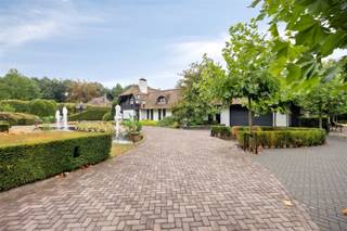 <p>Uitnodigende duo-villa op 8.843 m² op toplocatie in de gegeerde residentiële villawijk bij de NL-grens.</p><p>In 2023 totaal vernieuwd en klaar voor nieuwe bewoners staat deze prestigieuze villa (ca. 610 m² woonruimte) met rieten kap misschien wel op jou te wachten: Dat kan je beter niet te lang doen, want goeie dingen zijn snel weg.<br />Vooraan ontdek je direct de aantrekkelijke gevel en omkadering met vijvers en fonteinen. Vele auto's kan je er ook al parkeren, plaats genoeg.<br />Eénmaal binnen sta je verbluft naar de indrukwekkende marmeren traphal te kijken met glazen deuren naar de leefruimte. Deze is praktisch ingedeeld in verschillende knusse zithoeken en een eetkamer, allen met open haard. In de compleet ingerichte eetkeuken kan je je kookkunsten zeker tentoonstellen. De bijkeuken is gewoon handig erbij. Verder passeren we een gastentoilet, een master met veel inbouwkasten, dressings en een badkamer met alle faciliteiten spreekt direct aan om je dagelijkse verwenbeurt te genieten. Aansluitend is er een studio met living, badkamer, dressing, berging, extra keuken en woonkamer en toilet. Ideaal voor een inwonend familielid of personeel. Boven zijn e nog 4 slaapkamers met badkamers, dressings, 2 balkons en een woonkamer. Het lijkt wel een multi-huis met al deze ruimtes. Perfect voor een nieuw samengesteld groot gezin, want dat kan natuurlijk ook. In de achtertuin weet je niet waar eerst naar kijken: een serre zwevend boven de vijver, een zen-woonwagen, een fitnesshobbygebouw, een jacuzzi, overdekt terras, een zandstrand met opbouw zwembad. Ook is er zelfs een paintball terrein, en de paardenstal dient natuurlijk voor het stallen van paarden of andere dieren. Overal in het huis zijn er airco's te vinden en is er ook vloerverwarming. Kortom, dit vraagt voor een bezoekje om dit alles te bekijken.</p><p>EPC label B</p><p>Allerlei:<br />- Dubbele oprit<br />- Unieke vijverpartij met fonteinen<br />- Geboorde put versus grondwater<br />- Elektrische zonnewering<br />- Vele airco's<br />- Alarm<br />- Vele inbouwkasten<br />- Conform elektriciteitsattest<br />- Geen astbest<br />- Mogelijkheid voor het houden van paarden<br />- 2 balkons met knap uitzicht<br />- 6 slaapkamers<br />- 4 badkamers <br />- Bijzondere bijgebouwen</p><p>- Kangoeroewoning</p><p>- Beneden bewoning is mogelijk</p><p>- Kantoor aan huis is mogelijk</p><p>Vg, Wp/Agr, Gmo, Gvkr, Gvv. Alle informatie onder voorbehoud van vergissingen en wijzigingen. Oppervlaktes zijn indicatief.<br />Dit is geen aanbod, maar een onderhandelingsvoorstel.</p>