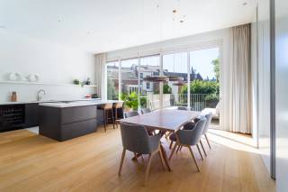 Achter de authentieke gevel van dit herenhuis bevindt zich op de eerste verdieping een stijlvol appartement, gelegen in de Belegstraat, op een gegeerde locatie die het bruisende Zuid en de geliefde Markgravebuurt met elkaar verbindt. Vanuit deze centrale ligging bevinden gezellige koffiebars, restaurants en lokale handelszaken zich op wandelafstand, net als de Troonplaats, de Amerikalei en het KMSKA. Ook het stadscentrum en de belangrijkste invalswegen zijn vlot bereikbaar.<br /><br />Via de inkomhal, voorzien van ingemaakte kasten, betreedt u de royale leefruimte. Dankzij de volledig beglaasde achterzijde geniet deze aangename ruimte van een overvloed aan natuurlijk licht. De parketvloer en moderne gashaard zorgen voor een warme en verfijnde sfeer. De leefruimte sluit naadloos aan op de open keuken met royaal kookeiland, die als centraal element van de woning fungeert. De keuken werd uitgerust met een hoogwaardige selectie Miele-toestellen, waaronder een steamer en wijnkoeler, en wordt vervolledigd door een Quooker. Aansluitend bevindt zich een praktische berging met aansluitingen voor wasmachine en droogkast, ideaal voor extra voorraad en opbergruimte.<br /><br />Vanuit de leefruimte heeft u rechtstreeks toegang tot het aangename, zuidgerichte terras. Het zicht op de Sint-Michielskerk en de omliggende tuinen zorgt bovendien voor een bijzonder groen en rustig kader, midden in de stad.<br /><br />De masterbedroom bevindt zich aan de voorzijde van het appartement en geeft uit op een charmant Frans balkon. De kamer beschikt over een volledige wand aan ingemaakte kasten, goed voor een zee aan opbergruimte. Daarnaast bevindt zich een tweede volwaardige slaapkamer, eveneens voorzien van ingemaakte kasten en flexibel in te richten als kinderkamer of bureau.<br /><br />De smaakvolle badkamer werd afgewerkt met hoogwaardige materialen, waaronder natuursteen en Vola-kranen. Een ruime inloopdouche met infraroodfunctie, dubbele wastafel en vrijstaand ligbad creëren hier een luxueuze en comfortabele ruimte.<br /><br />Tot slot beschikt het appartement over een private kelderberging, inbegrepen in de prijs. Een inpandige autostaanplaats is bij aan te kopen voor € 45.000.<br /><br />Interesse in deze parel?<br />Contacteer LISTED voor een bezoek: +32 3 283 51 51.