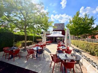 In het centrum van Vlamertinge bevindt zich deze recente opbrengsteigendom (bj. 2015), bestaande uit een volledig uitgeruste café/brasserie, een ruim 3-slaapkamerappartement en drie verhuurde garageboxen.<br /><br />De horecazaak omvat een caféruimte van ca. 50 m² met aansluitend een toog van ca. 15 m² en biedt plaats aan ongeveer 50 personen. Verder is er een basiskeuken, koelcel, droge kelder van ca. 17,3 m² met liftsysteem voor zware goederen en uitgebreid sanitair met afzonderlijk mannen-, vrouwen- en andersvalidetoilet. Vooraan bevindt zich een terras van ca. 11 m² en achteraan een ruim terras van 90 m² met aansluitend een speelplein van 40 m². De zaak wordt volledig uitgerust aangeboden en is vrij van brouwerijverplichting.<br /><br />Het bovenliggende appartement beschikt over een ruime leefruimte met open ingerichte keuken en kookeiland van 60,60 m², een berging van 5 m², apart toilet en een terras van 28 m². Op de eerste verdieping bevinden zich drie slaapkamers van 14,30 m², 9 m² en 7,50 m², een badkamer van 8,70 m² met ligbad, inloopdouche en dubbele wastafel, en een afzonderlijk toilet. De tweede verdieping omvat een geïsoleerde zolder van ca. 22 m², bereikbaar via een valtrap.<br /><br />Extra troeven zijn de vloerverwarming via lucht-waterwarmtepomp, aluminium schrijnwerk, gunstig EPC B (139 kwh/m²) voor het appartement en de handelszaak heeft een A-label EPC, alarmsysteem, projector en twee regenwaterputten van elk 10.000 liter.<br /><br />Tot slot behoren er drie verhuurde garageboxen met sectionale poort tot het eigendom, goed voor een bijkomende huuropbrengst. Deze kunnen optioneel bijgekocht worden en in eerste instantie wordt afgewacht of de kopers van het gebouw die wensen bij te kopen.<br /><br />Een veelzijdige eigendom met een sterke combinatie van wonen, ondernemen en investeren op een centrale ligging in Vlamertinge.