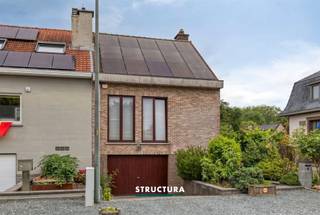 In een rustige doodlopende straat in Wemmel bevindt zich deze verrassend ruime halfopen bebouwing op een perceel van ca. 3a63ca. Met een bewoonbare oppervlakte van ongeveer 204 m², een praktische indeling over verschillende niveaus, een groene tuin met veel privacy en een uitstekende energiescore (EPC B) dankzij de zonnepanelen en thuisbatterij, biedt deze woning een ideale combinatie van ruimte, comfort en energiezuinig wonen.Indeling- Gelijkvloers: via de inkomhal betreedt u de woning. Op deze verdieping bevinden zich een afzonderlijk toilet, een wasberging met douche, een kelderberging, de garage en een extra kamer die perfect kan dienen als slaapkamer, bureau of hobbyruimte.- Eerste verdieping: deze vormt het hart van de woning en omvat een aangename leefruimte met gezellige cassettehaard op hout, een keuken, een slaapkamer, een badkamer en een afzonderlijk toilet.- Zolderverdieping: werd ingericht als een volwaardige zolderkamer en biedt extra mogelijkheden als slaapkamer, bureau of ontspanningsruimte.- Exterieur: vanuit de keuken heeft u toegang tot een terras. Via een trap bereikt u vervolgens de lager gelegen tuin, die eveneens toegankelijk is vanuit de wasberging op het gelijkvloers. De tuin geniet van veel groen en privacy, waardoor u er in alle rust kunt genieten. Daarnaast beschikt de woning over een parkeerplaats op de oprit en zijn er extra parkeermogelijkheden voor de deur.Karakteristieken- UITSTEKENDE ligging- EPC-label B- Zonnepanelen met thuisbatterij - warmtepomp L/L- Elektrische installatie conform tot 2044- Maatregelen in het maatregelenregister: nee- regenwaterrecuperatieBent u op zoek naar een ruime, energiezuinige woning op een rustige locatie in Wemmel, met een praktische indeling en een aangename tuin? Dan is deze woning absoluut een bezoek waard. Contacteer ons vandaag nog voor meer informatie of een bezichtiging via 02 460 80 46 of info@structura.be